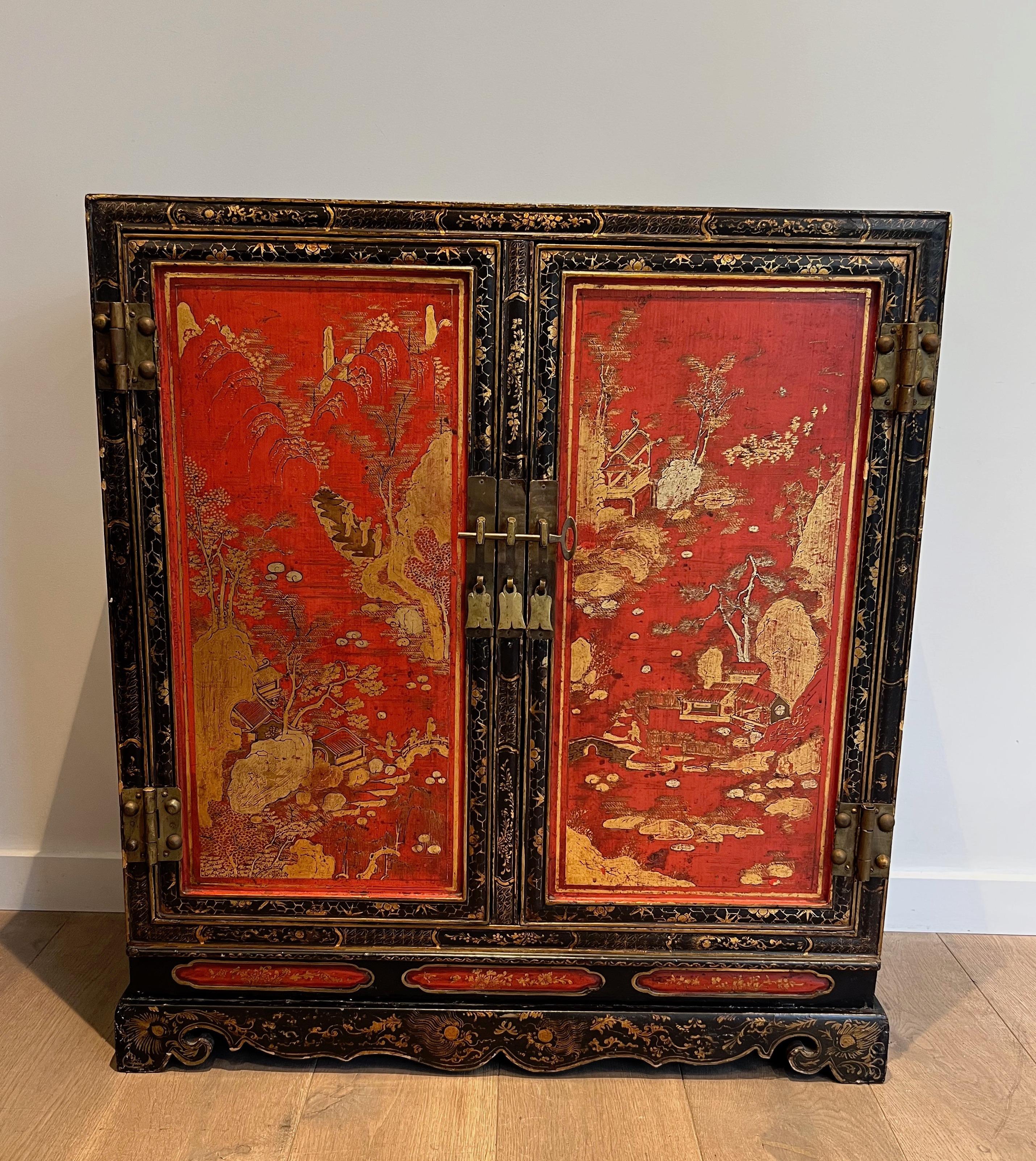Dieser schöne zweitürige Schrank ist aus schwarz und rot lackiertem Holz gefertigt und zeigt chinesische Symbole und Dekorationen in Goldtönen. Dies ist ein französisches Werk. CIRCA 1940