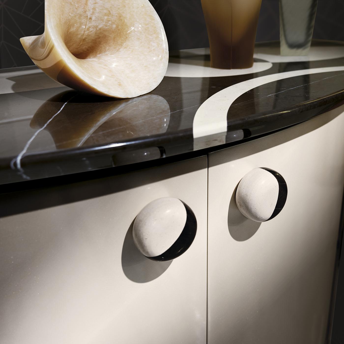 A testament to functional artistry, this ellipse-shaped console redefines bedroom storage with its impeccable craftsmanship. Expertly crafted from lacquered wood, its dual-tone marble top and handles exude modern opulence, elevating the aesthetic of