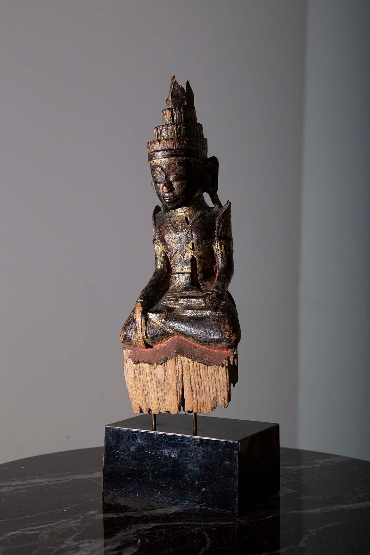 In the midst of the 18th century, in the enchanting land of Burma during the Shan period, a magnificent masterpiece of spiritual artistry was born—an extraordinary Seated Burmese wooden crowned Buddha, often referred to as the 