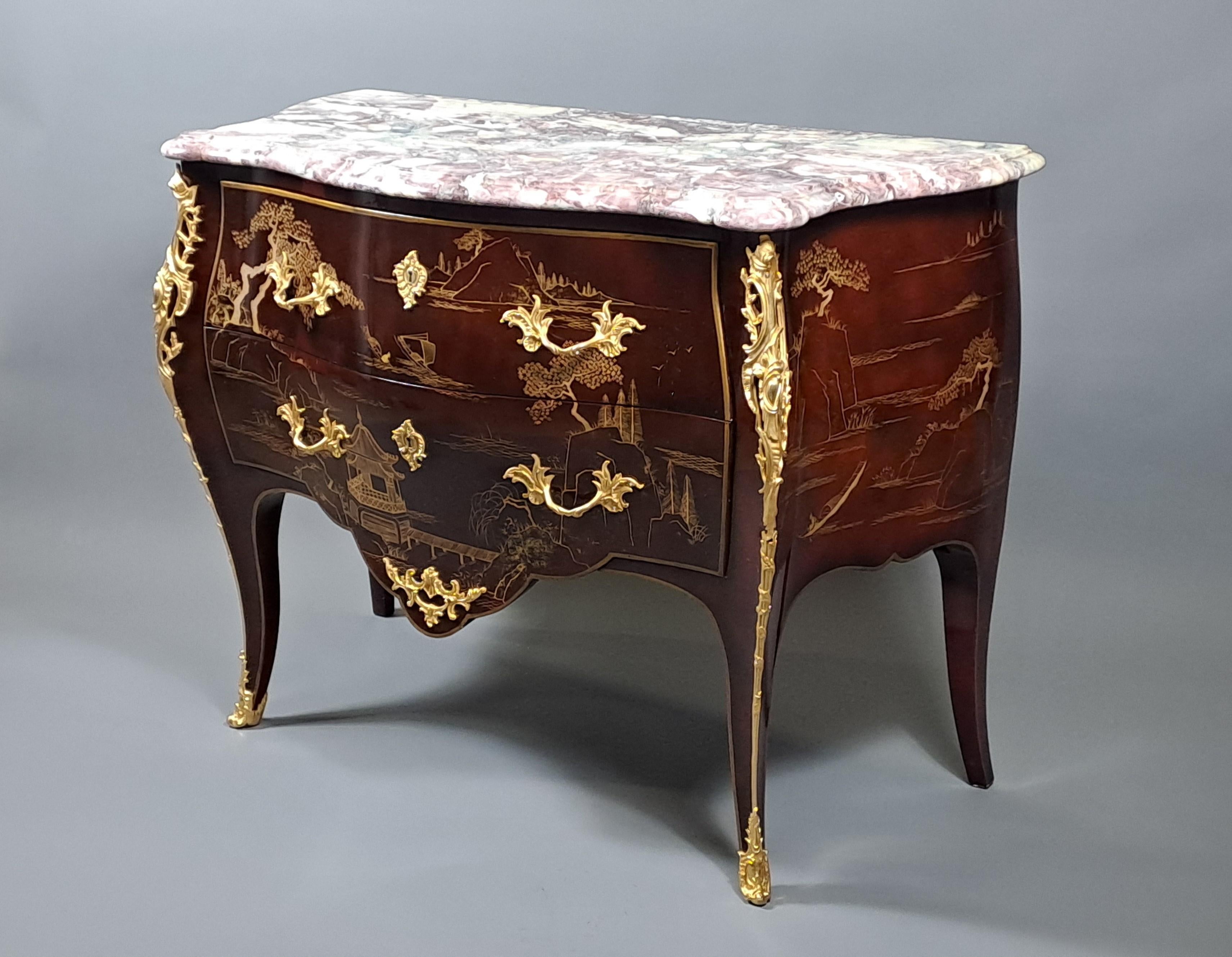 Bellissima commode in stile Luigi XV in legno laccato e riccamente decorato in oro con paesaggi lacustri in stile cinese, ricca ornamentazione in bronzo dorato finemente cesellato, sormontata da un bellissimo fiore di pesco in marmo modellato a