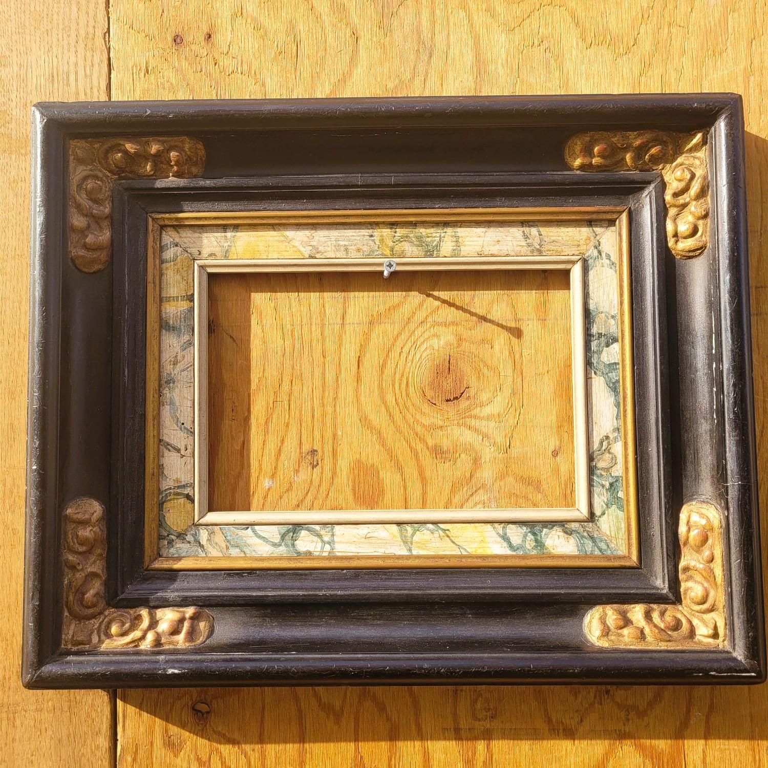 Black and gold lacquered wooden frame, painted to resemble marble, in the 17th-century style.   

Wear and chips consistent with age.  

Ideal for a mirror ( sold as a frame, no mirror included).  

Late 19th/early 20th century.   

Frame