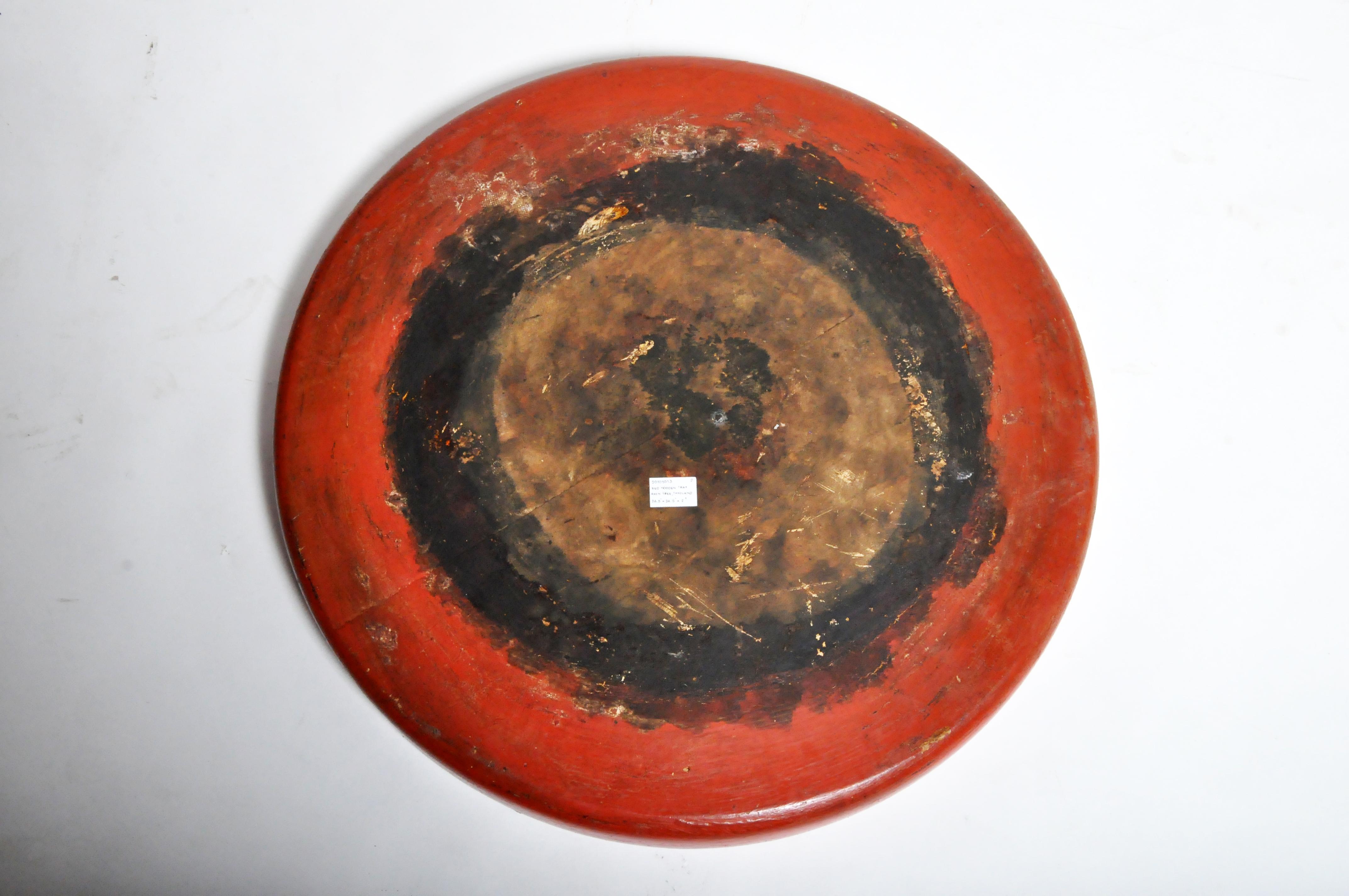 This large wooden tray was carved from a single piece of teak wood and covered in multiple layers of natural tree sap lacquer. Black lacquer was used to fill in the pores of the wood and build up a thick, protective surface. Red cinnabar lacquer