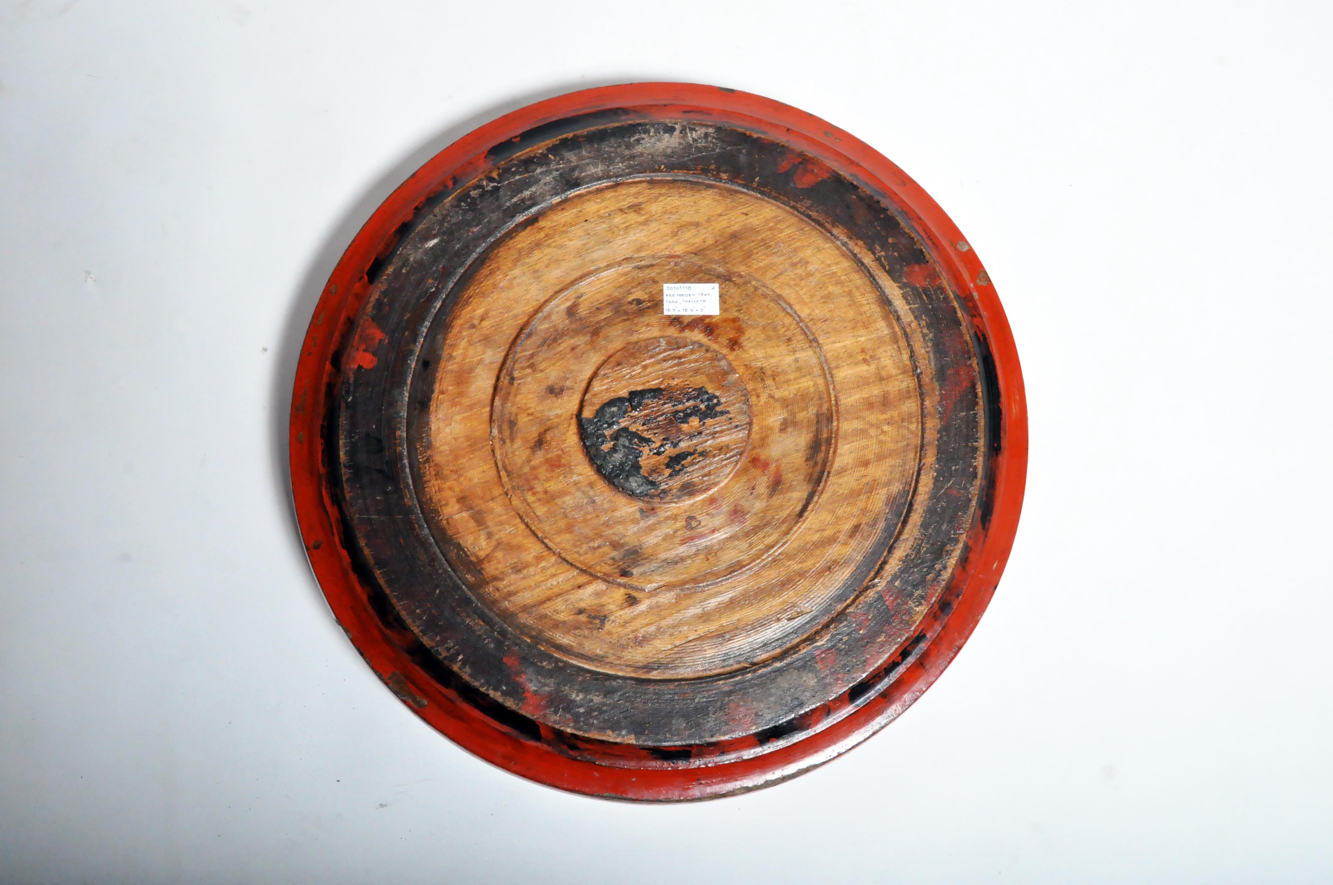 This large wooden tray was carved from a single piece of teak wood and covered in multiple layers of natural tree sap lacquer. Black lacquer was used to fill in the pores of the wood and build up a thick, protective surface. Red cinnabar lacquer
