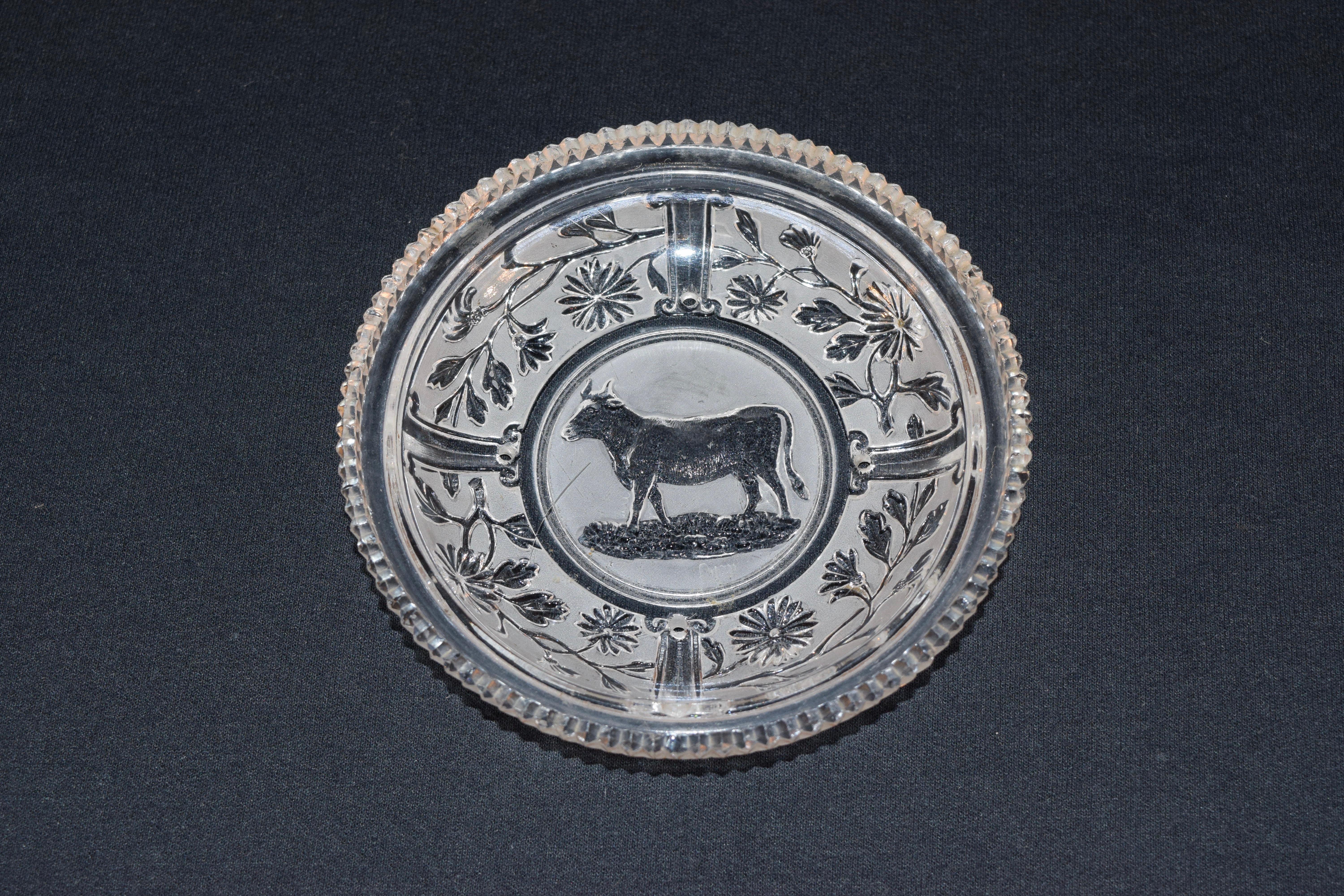 Lacy sandwich small dish with a central design of a cow. Lovely mold with a saw tooth edge and florals surrounding the central design.