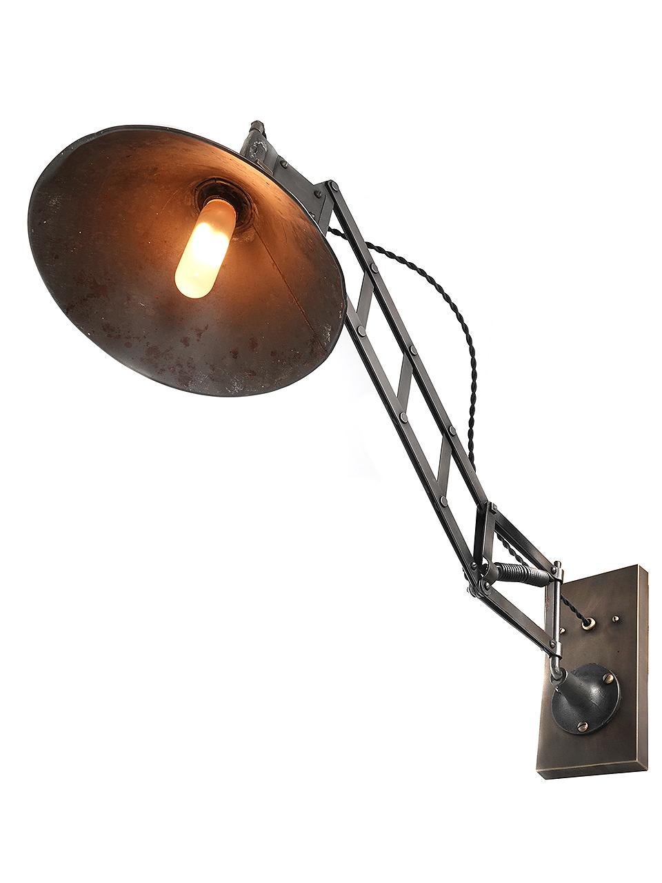 This work lamp has just the right look. The finish and patina is untouched and shows its history. I have never offered or found another example like this. The collapsing ladder and spring is very unique.