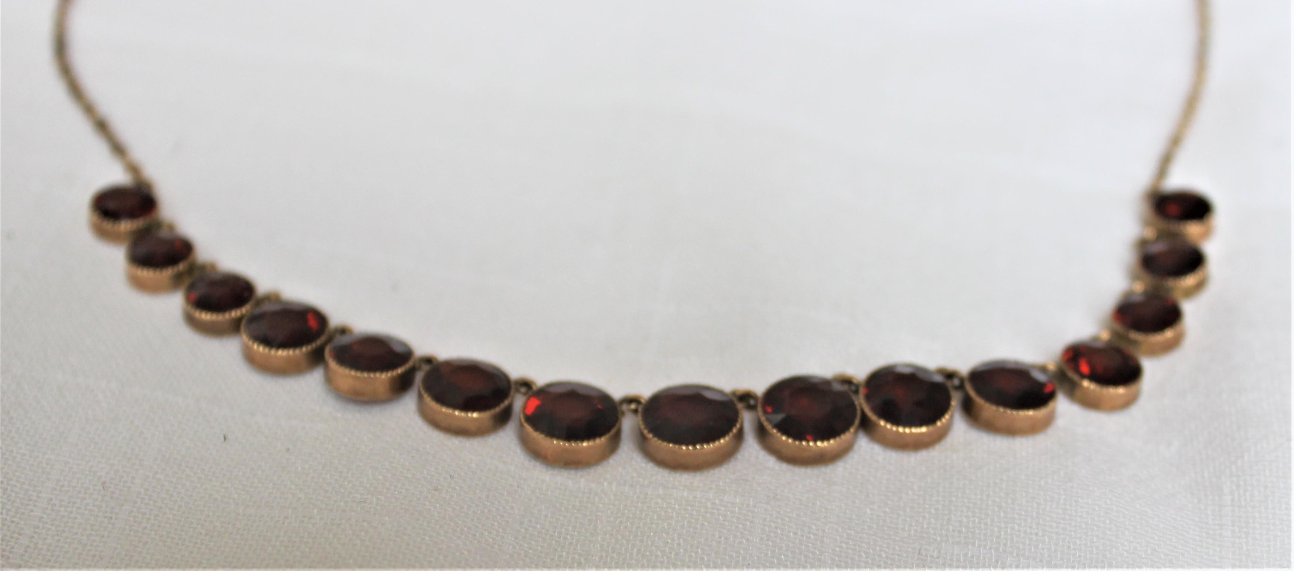This 10-karat rose gold necklace with deep fine toothed bezel set graduated garnets is completely unsigned, but tests for 10-karat gold and is believed to have been made in the Early 20th century in a modern style. The Bohemian garnets present with