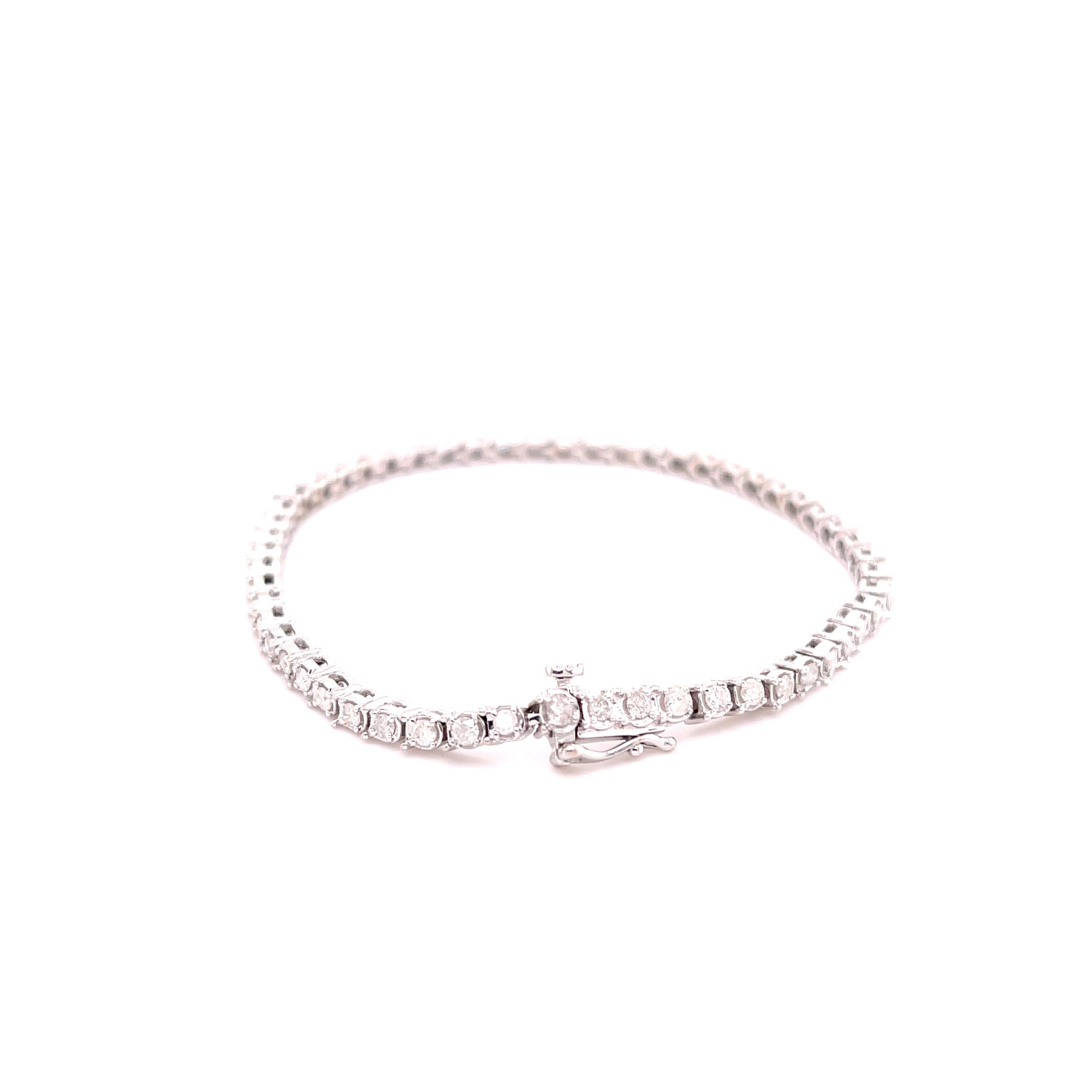 One lady's custom made polished rhodium plated 10K white gold, diamond tennis bracelet. The bracelet measures approximately 7.00 inches in length by 2.70mm in diameter and weighs a total of 9.80 grams. Stamped 
