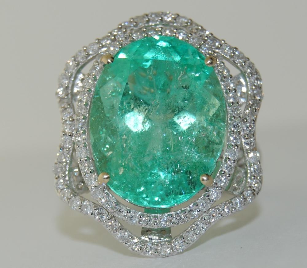 Ladies oval shape 12.72 carat Emerald surrounded with diamonds total weight 1.96 carat Ring is mounted in 18 Karat White Gold.  Ring size 7.