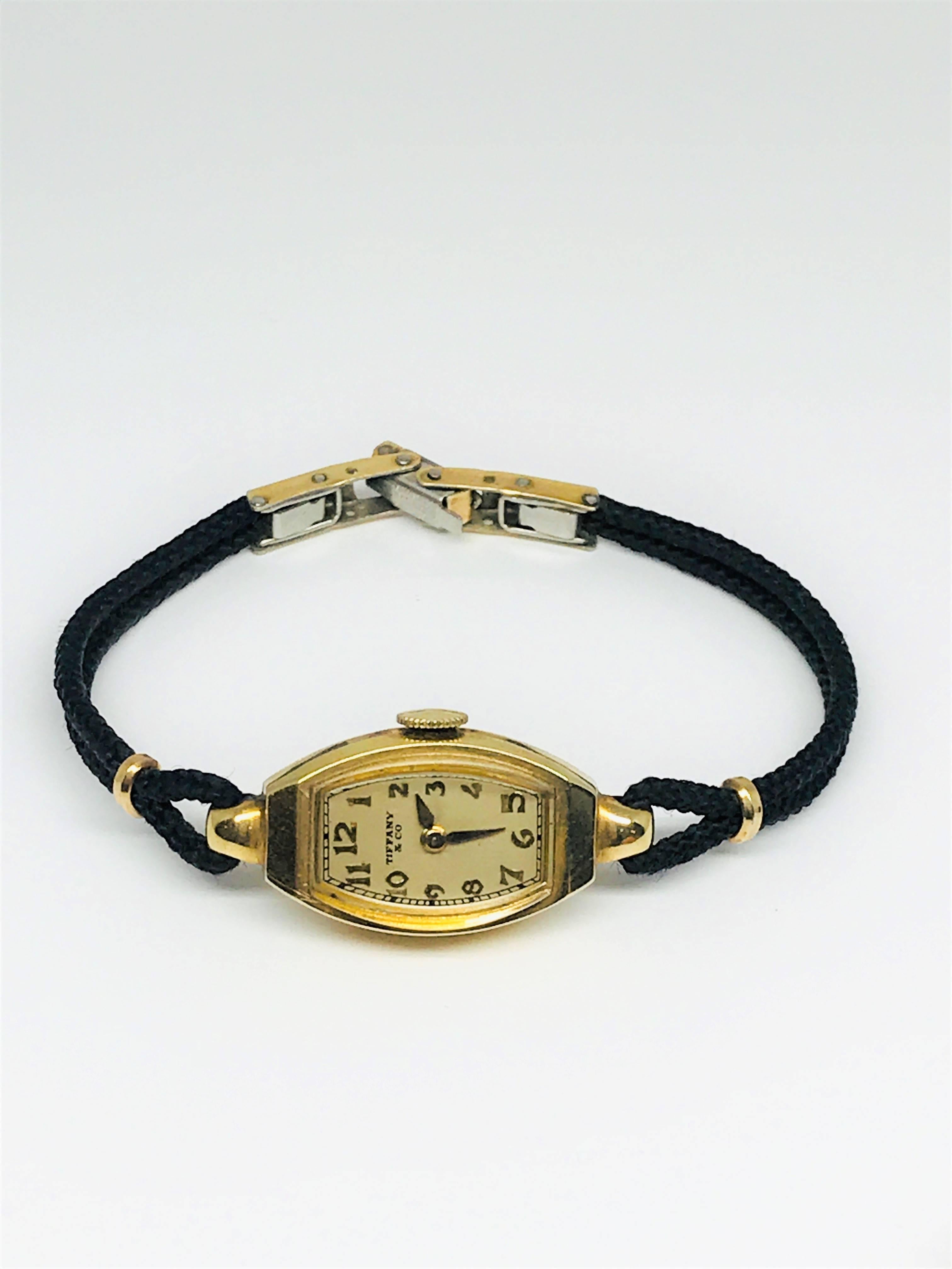 Super sweet ladies 14k gold wrist watch with black silk band. This watch was made by Hamilton for Tiffany & Co. The watch face is about and inch long and 1/2 inch wide. It is petite and so classic! Tiffany & Co never goes out of style and is the