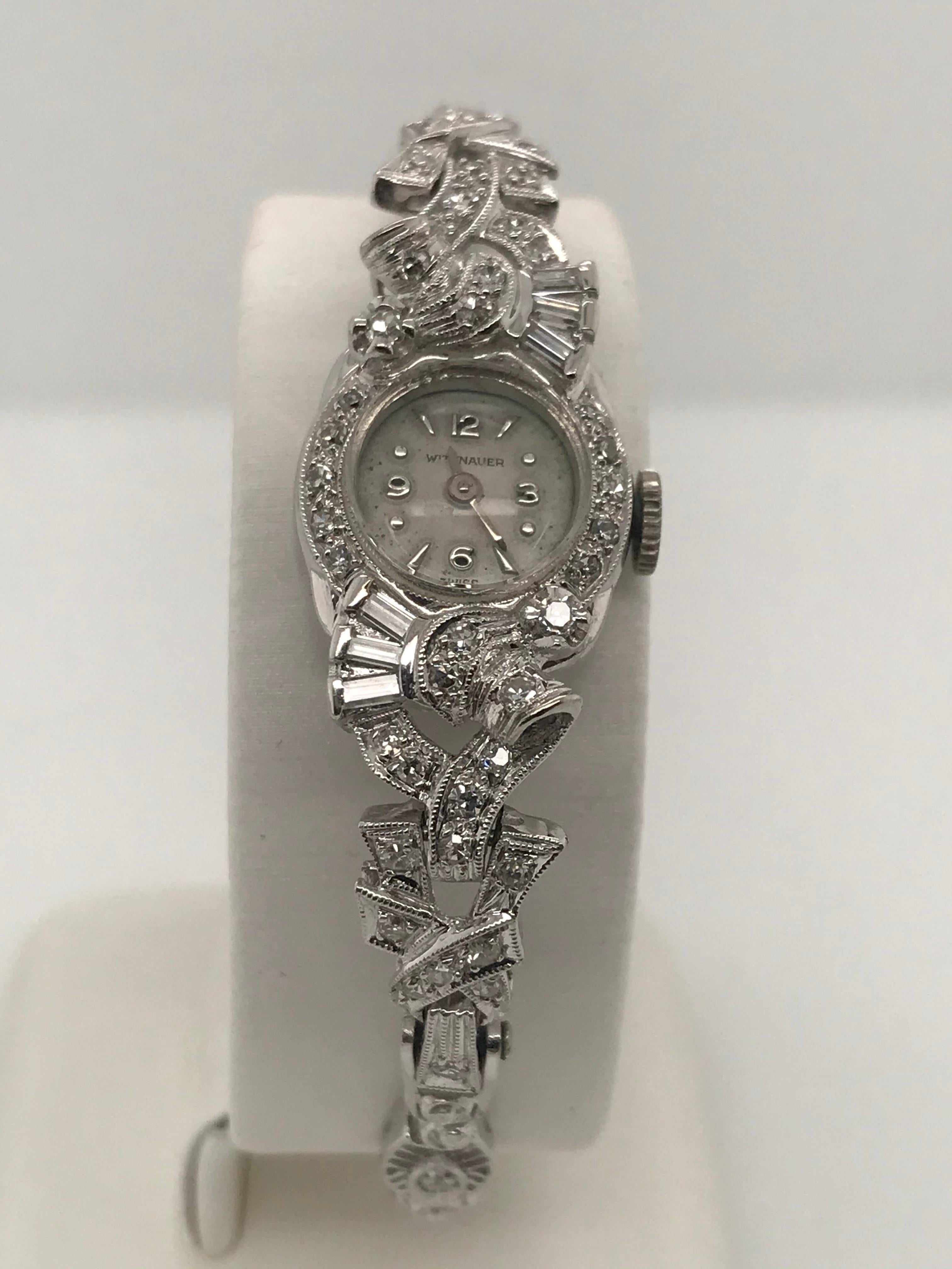14K white gold 17 jewel Swiss movement Wittnauer watch with 44 single cut diamonds, 8 round brilliant cut diamonds and 6 baguette diamonds with a total weight of approximately 0.67cts. It has a delicate filigree link bracelet with fold over clasp.
  