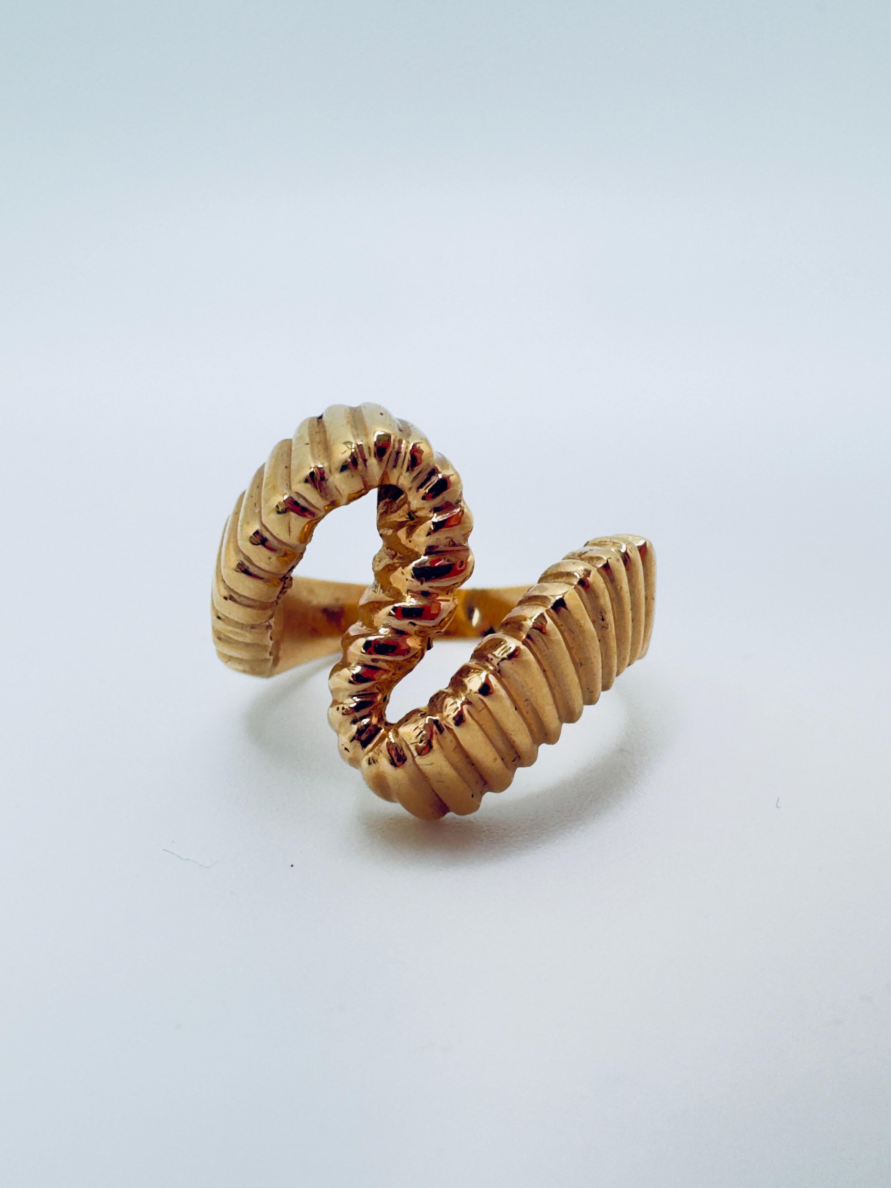 Este anillo de mujer está fabricado en oro amarillo pulido de 14 quilates y diseñado en una llamativa forma de 