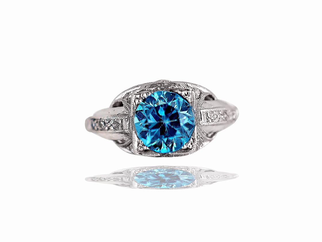 This stunning diamond ring has one round blue zircon that weighs 1.50 carats and measures 7 mm aprx.  The center stone is complimented by a carefully pierced platinum Deco mounting and twenty single cut and European cut diamonds.  These stones range