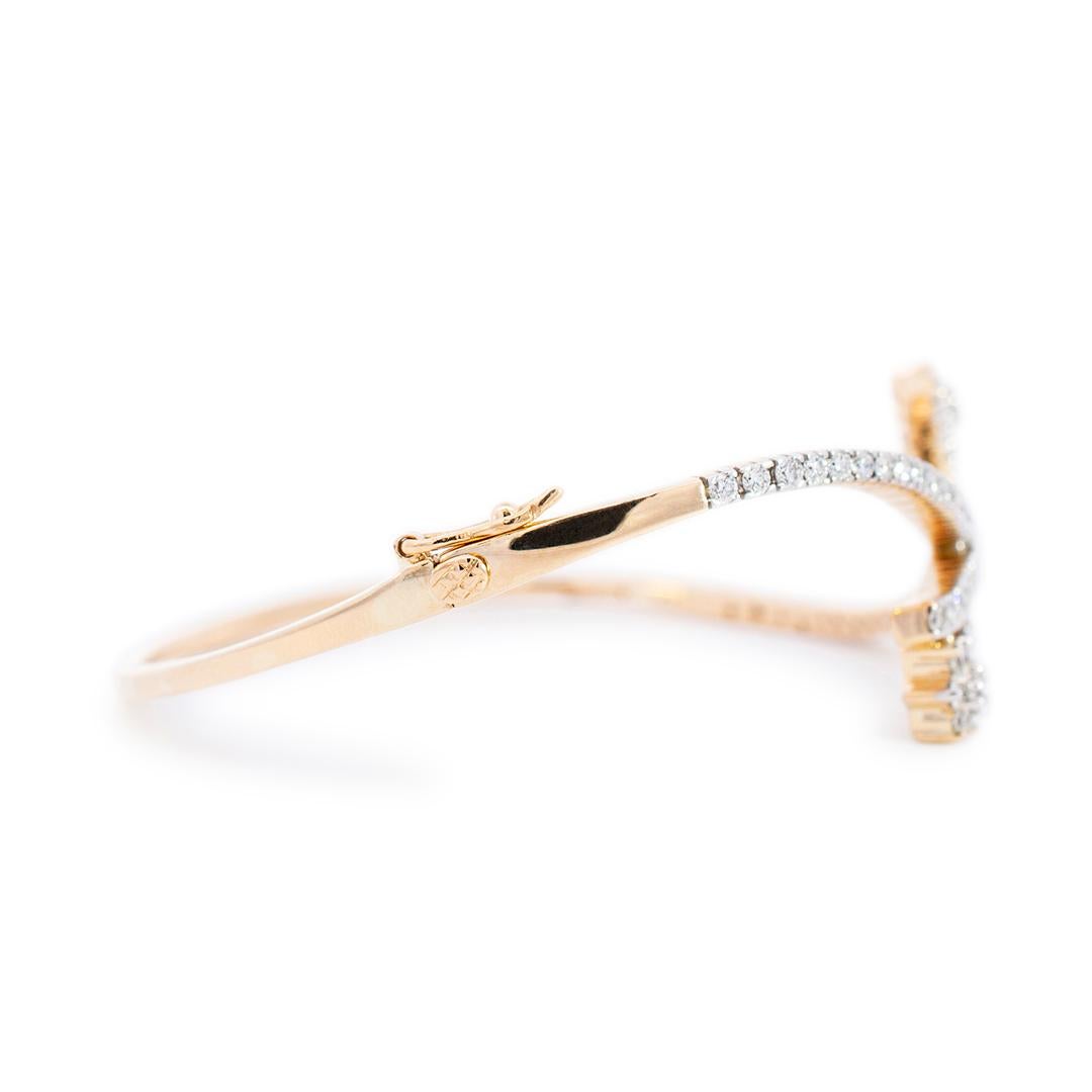 Lady's custom made polished 18K yellow gold, diamond bangle bracelet. The bracelet measures approximately 6.00 inches in length by 24.90mm tapering to 1.75mm in width and weighs a total of 12.77 grams. Engraved with 