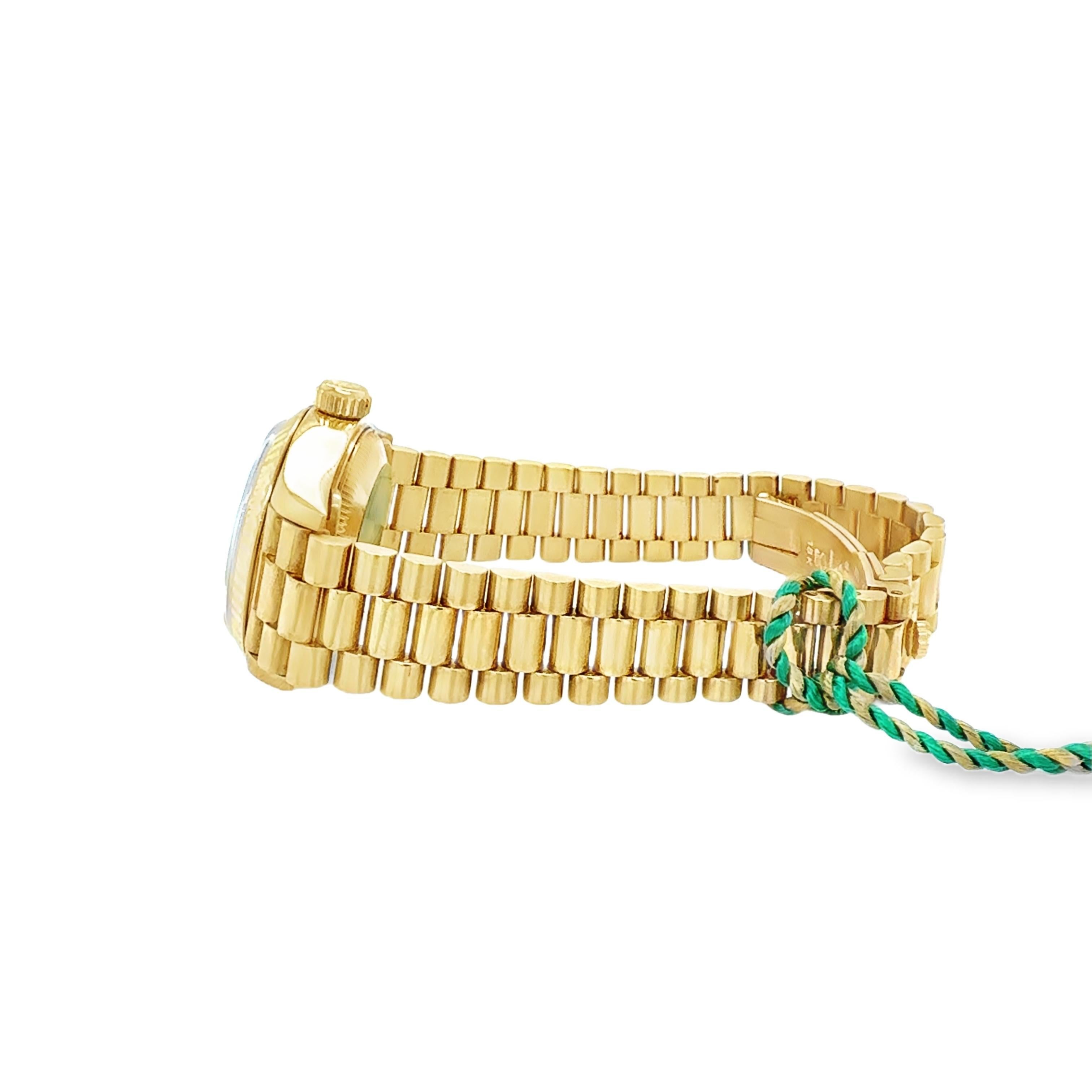 Diese exquisite Rolex President Damenarmbanduhr aus 18 Karat Gelbgold verbindet zeitlose Eleganz mit außergewöhnlicher Handwerkskunst. Das Gehäuse mit seinem diamantbesetzten Zifferblatt und der kannelierten Lünette strahlt Raffinesse und Glanz aus.