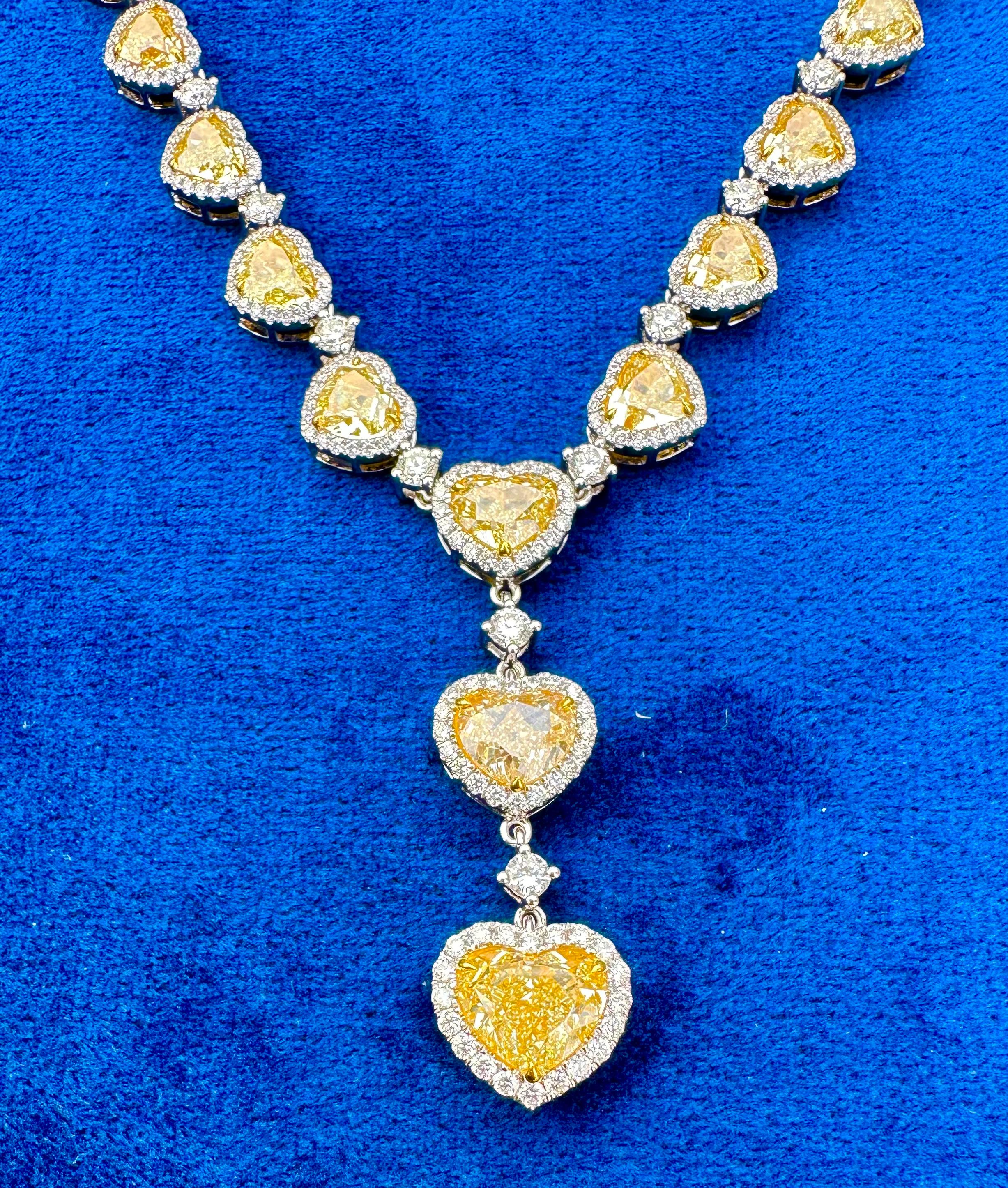 Captivating, approximately 43.48 carat natural yellow heart shaped diamond 18 karat white and yellow gold drop front lariat style necklace with a trilogy of three large heart shaped diamonds suspended from the middle, features a total of 29