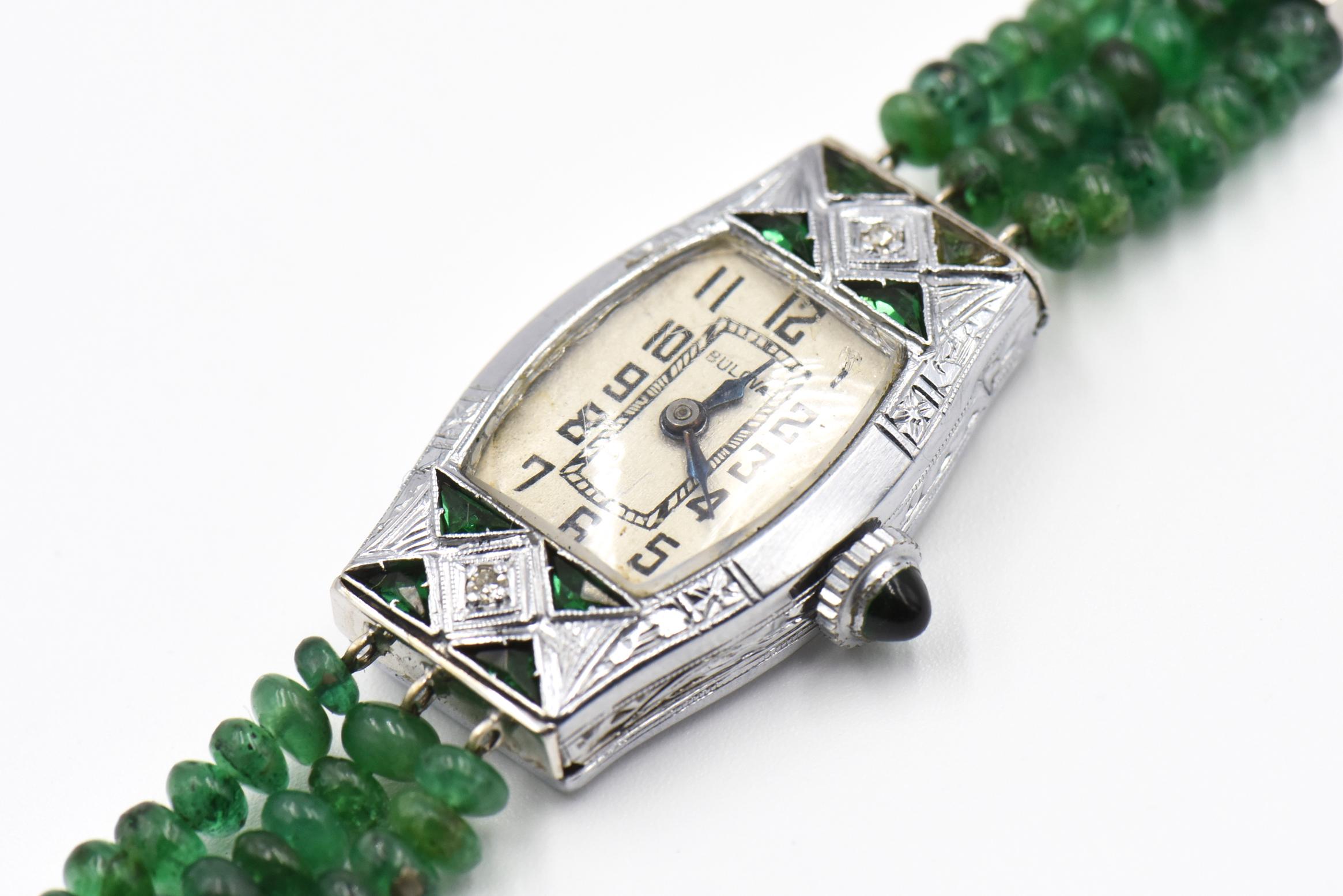 Art Deco diamond and emerald watch head set on newer triple-strand band of emerald beads with diamond spacers. Watch head, spacers and clasp are 14K white gold. The dial is signed Bulova.  This is a mechanical watch - it must be would when ever you