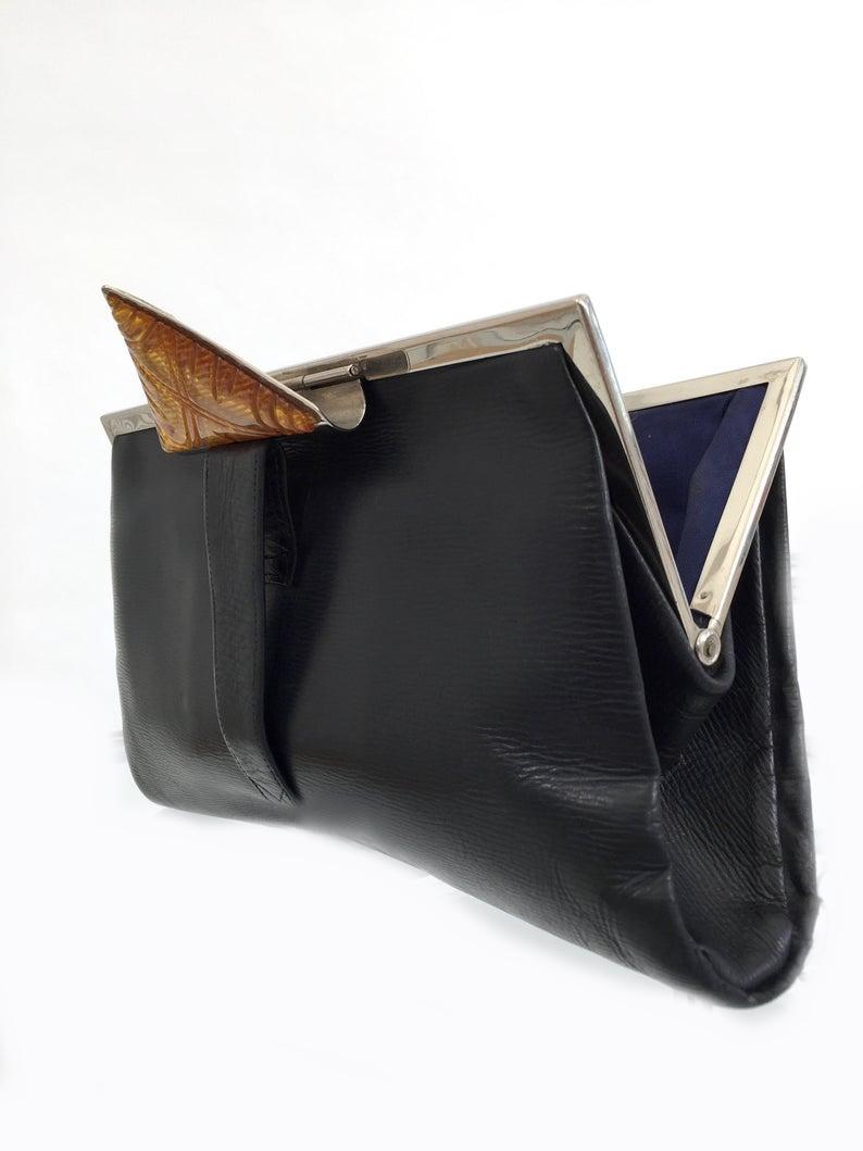 For your consideration is this superbly stylish and rare 1930s Art Deco dark navy blue leather handbag. Features a chrome frame and a large triangular carved Lucite clasp in glorious butterscotch color. Lined in a navy blue grosgrain silk with an