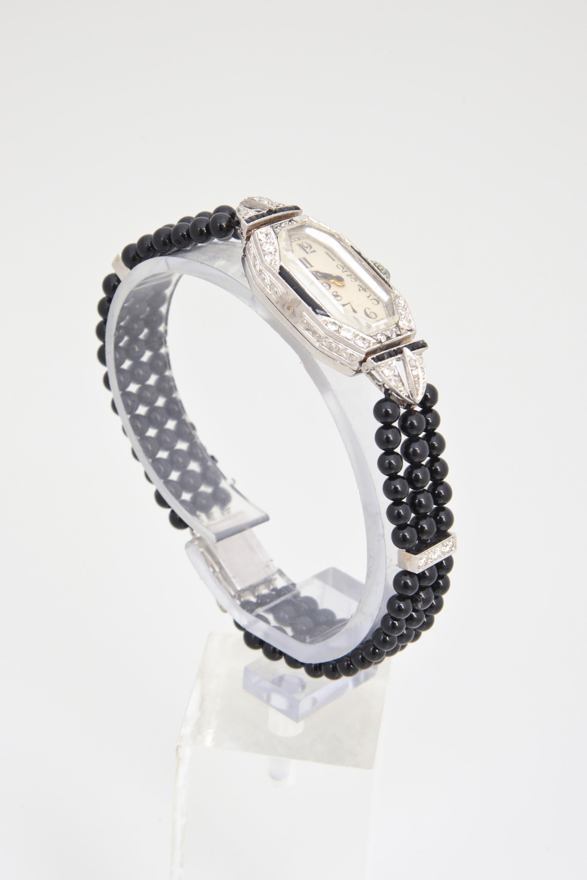 Uhrenkopf aus Diamanten und Onyx im Art-Deco-Stil, eingefasst in ein neueres, dreifach geflochtenes Band aus Onyxperlen mit Diamantabstandshaltern. Der Uhrenkopf ist aus Platin. Abstandhalter und Schließe sind aus 14 Karat Weißgold. Handgravur auf