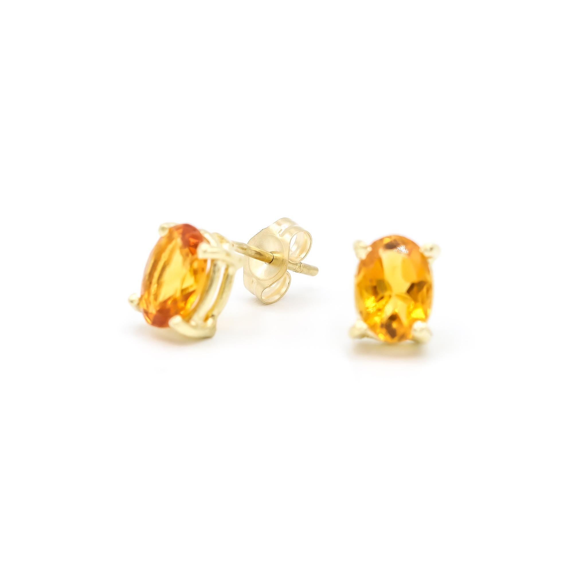 One pair of lady's custom made polished 14K yellow gold, diamond and citrine stud earrings with push backs. The earrings measure approximately 0.13 inches in length and weigh a total of 1.50 grams. Engraved with 