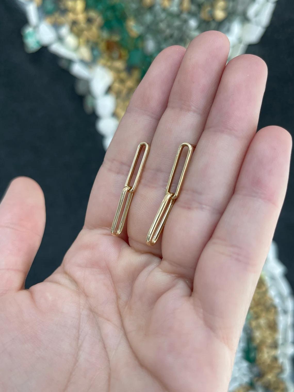 These captivating women's paperclip dangle earrings showcase a unique design with two interconnected paperclips gracefully dangling from each other. Meticulously crafted in 14k yellow gold, these earrings offer a modern and stylish twist to a