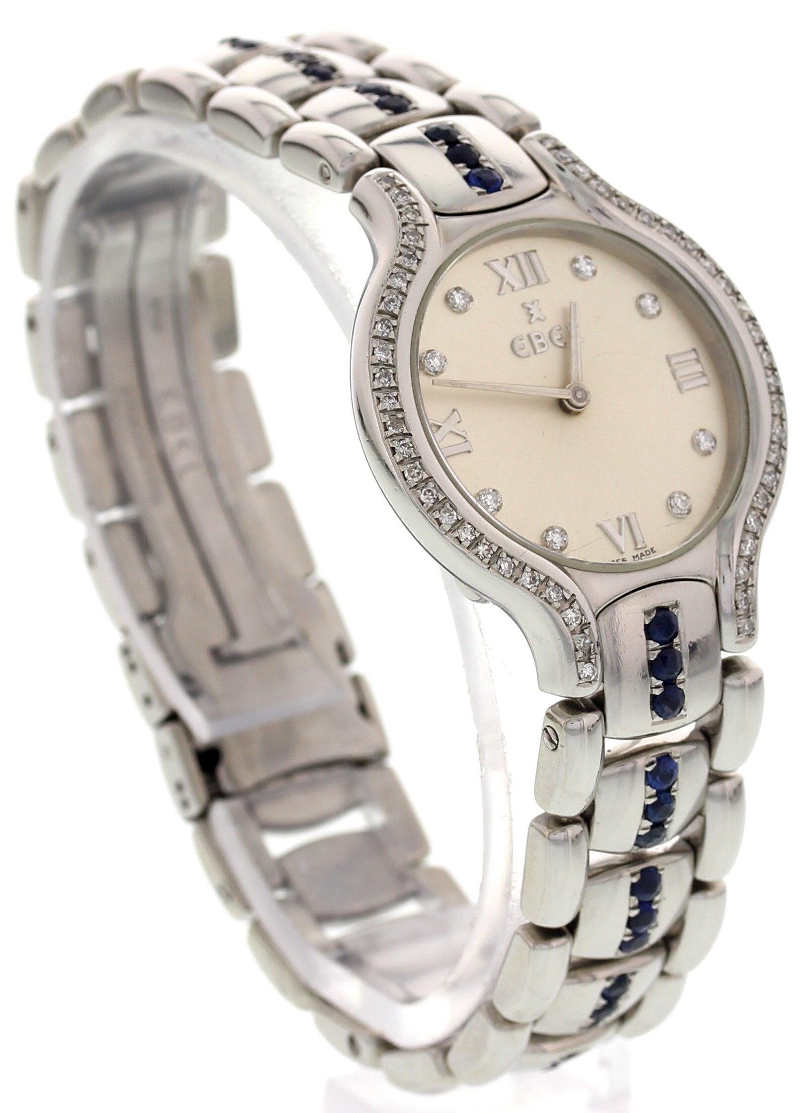 Stainless steel 26 mm case. Stainless steel bracelet with sapphires. Hidden folding clasp. Round cut diamonds around the stainless steel bezel. Silver dial with diamonds and silver roman numeral markers at the 12, 3, 6, and 9 hours. Quartz movement.
