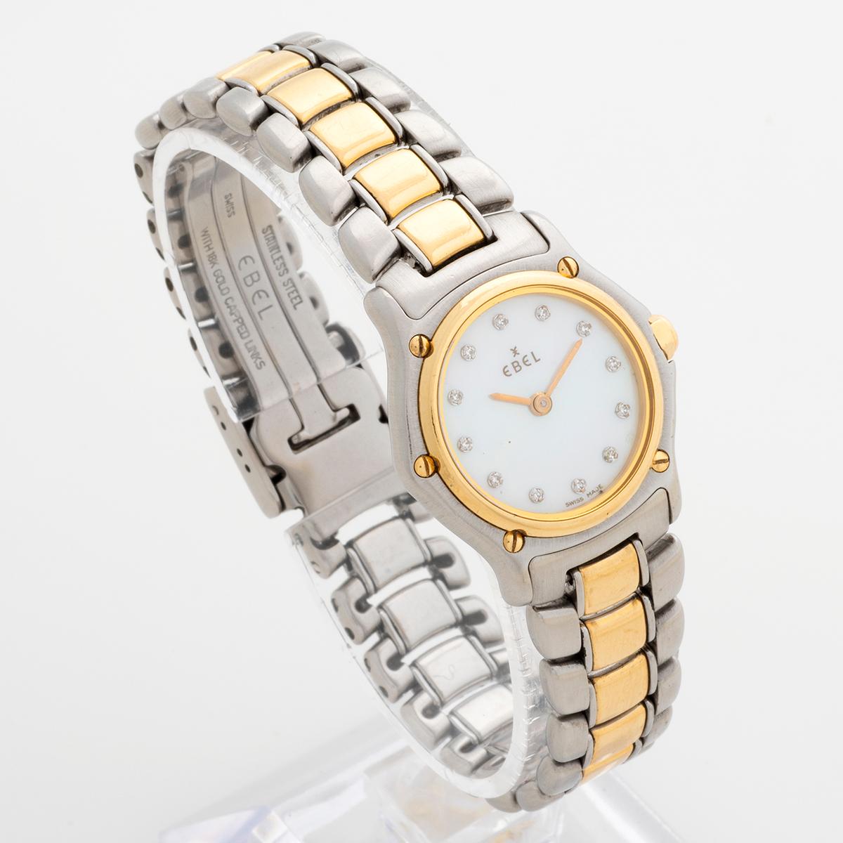 Our ladies Ebel mini sport features a 25mm stainless steel case with 18k yellow gold bezel, and a 1911 style sport bracelet in gold/steel. Of note is the very attractive mother of pearl dial with factory set diamond dot dial, with gold hands.