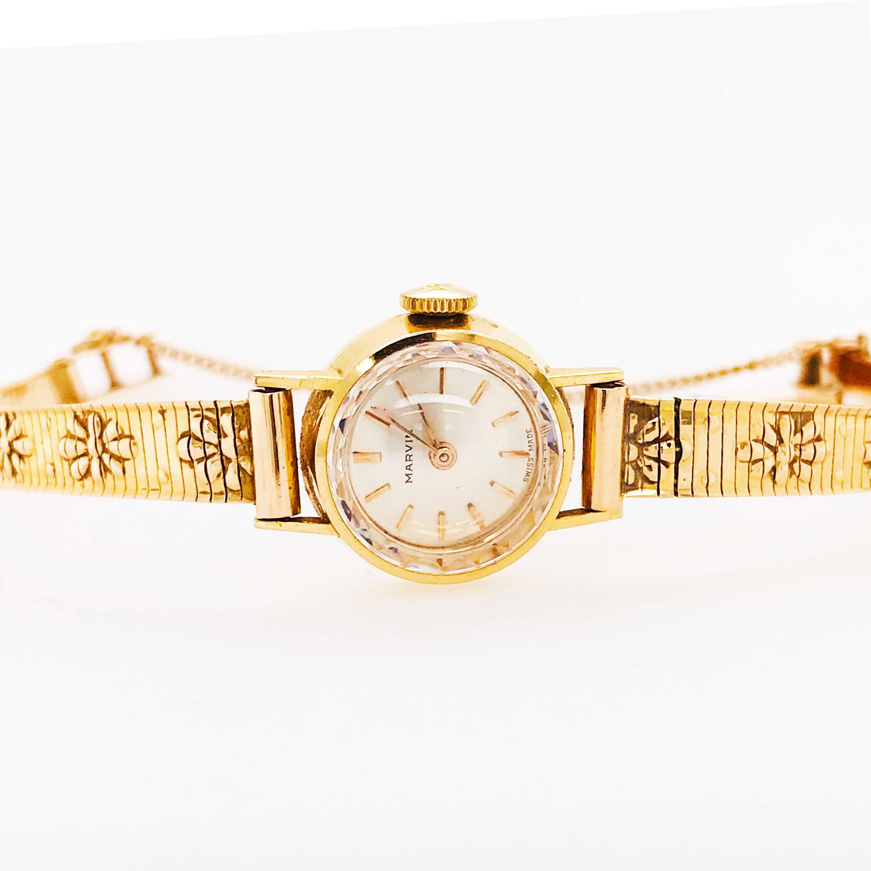 This 14 karat yellow gold ladies wristwatch is from Circa 1955. It has a lovely round case with fun flowers on the 14 karat yellow gold watch strap.  The white face (dial) is very easy to read and the facets on the crystal are quite charming!  The