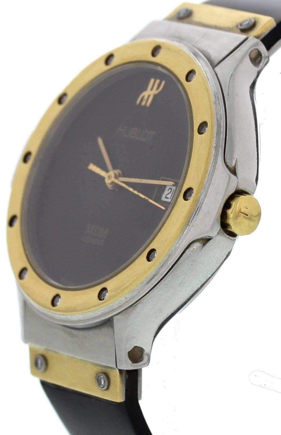 Ladies Hublot MDM. 28 mm stainless steel case. 18k yellow gold bezel and lugs. Black dial with gold hands. Date display. Black rubber strap with stainless steel hidden double folding clasp; will fit up to a 6 inch wrist. Quartz battery movement.