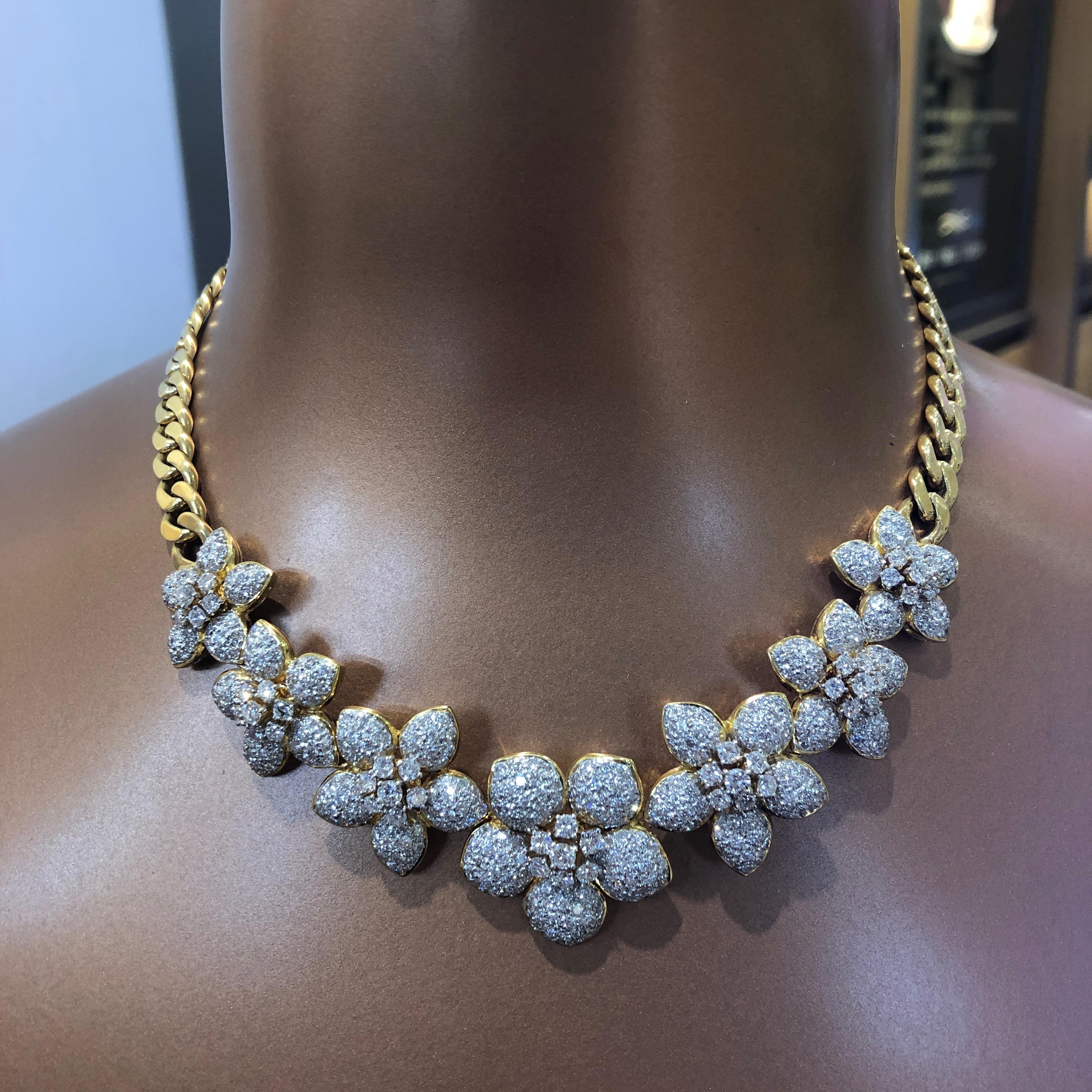 This one-of-a-kind diamond estate necklace features seven (7) pave diamond flowers and designed in 18 karat yellow gold. Each flower contains a diamond cluster center surrounded by pave petals. The flowers are attached to a heavy solid gold polished