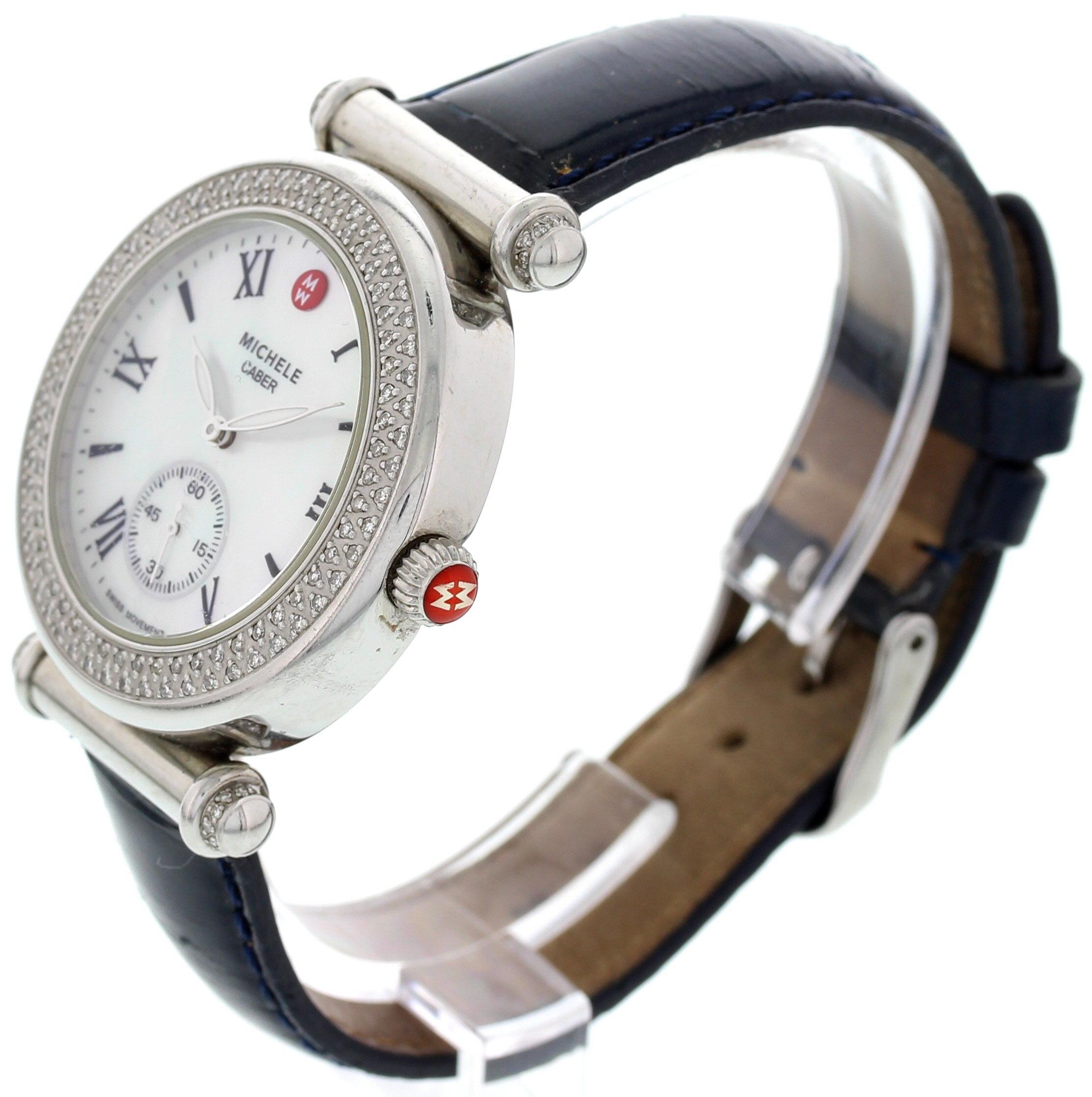 A ladies Michele Caber diamond bezel stainless steel watch with a seconds sub dial. The dial white mother pearl with roman numeral indexes. The band is an adjustable blue leather with a stainless steel buckle. Quartz movement.
