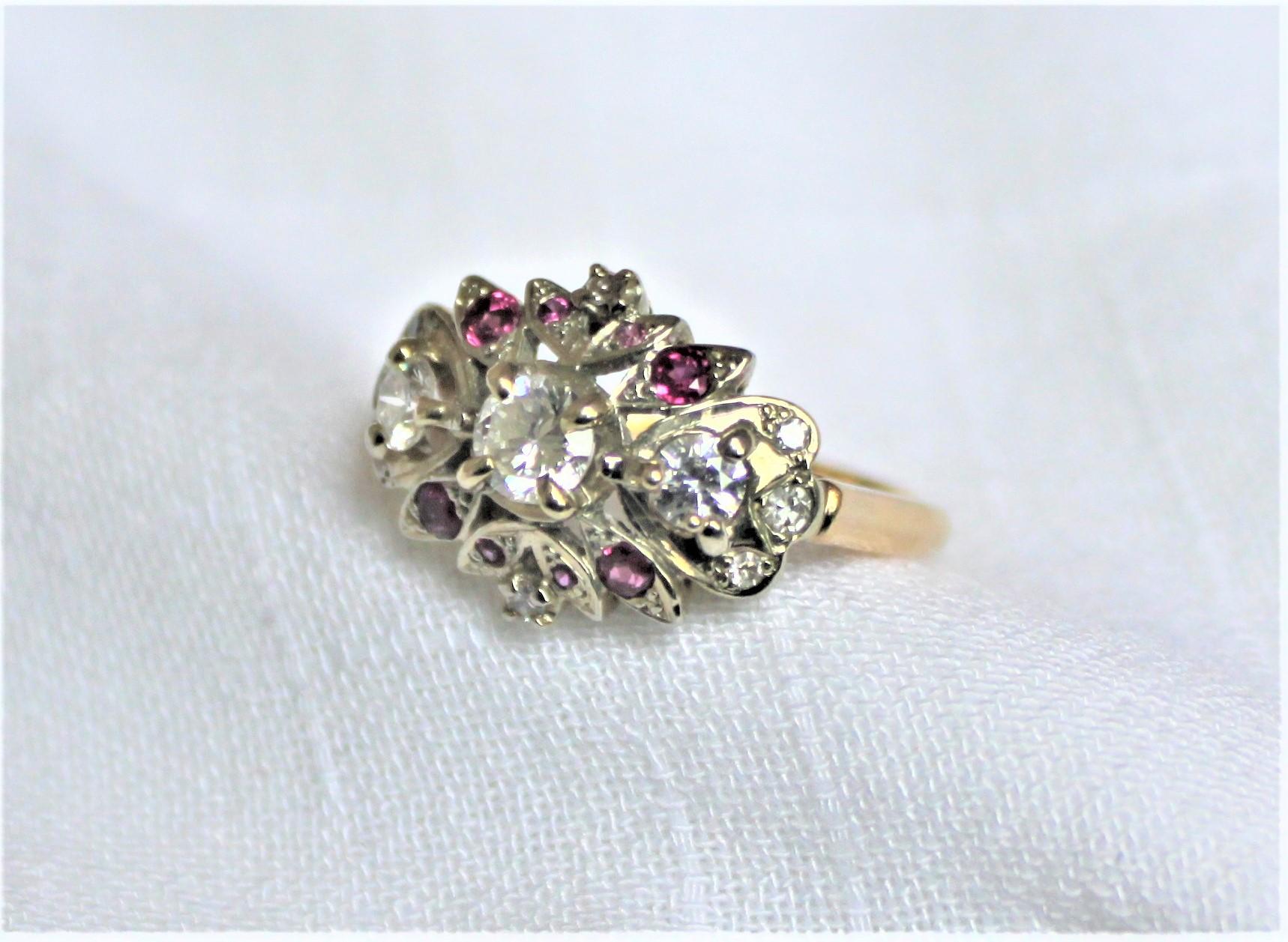 This ladies 14 karat yellow and 10 karat white gold cluster ring done with diamonds and rubies dates to the 1960's and is presumed to have been made in the United States. This ring features a prong set, brilliant cut diamond center stone rated at a