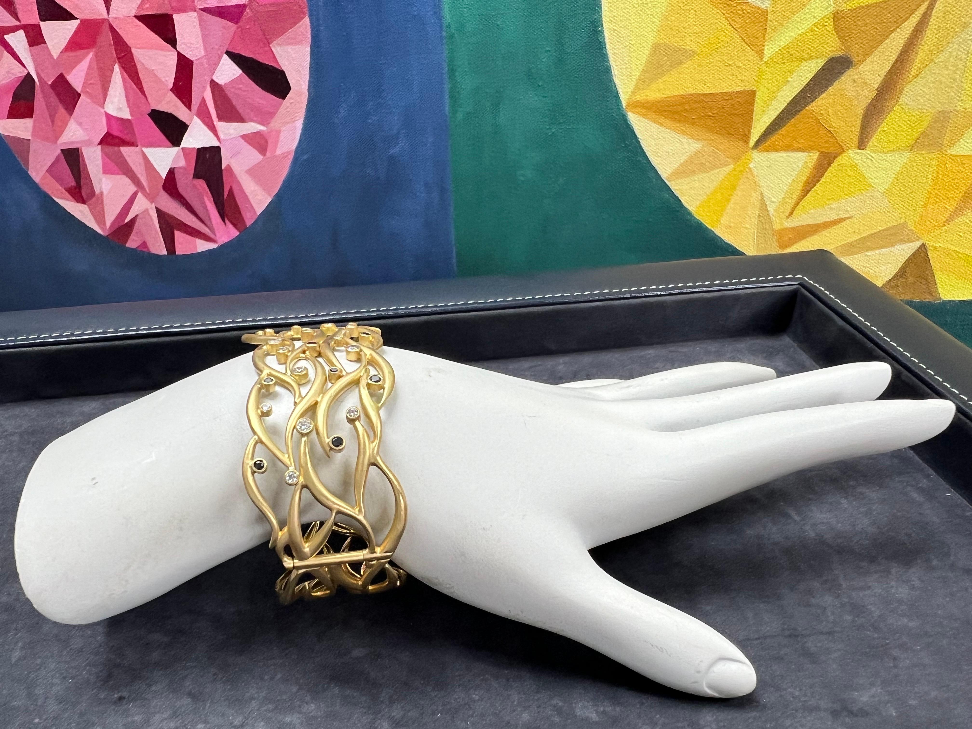 A magnificent 18k yellow gold bangle set with 17 natural colorless diamonds weighing approximately 0.70 carats and 11 black diamonds weighing approximately 0.35 carats.

The bangle measures 7 inches long within the inner circle and the total weight