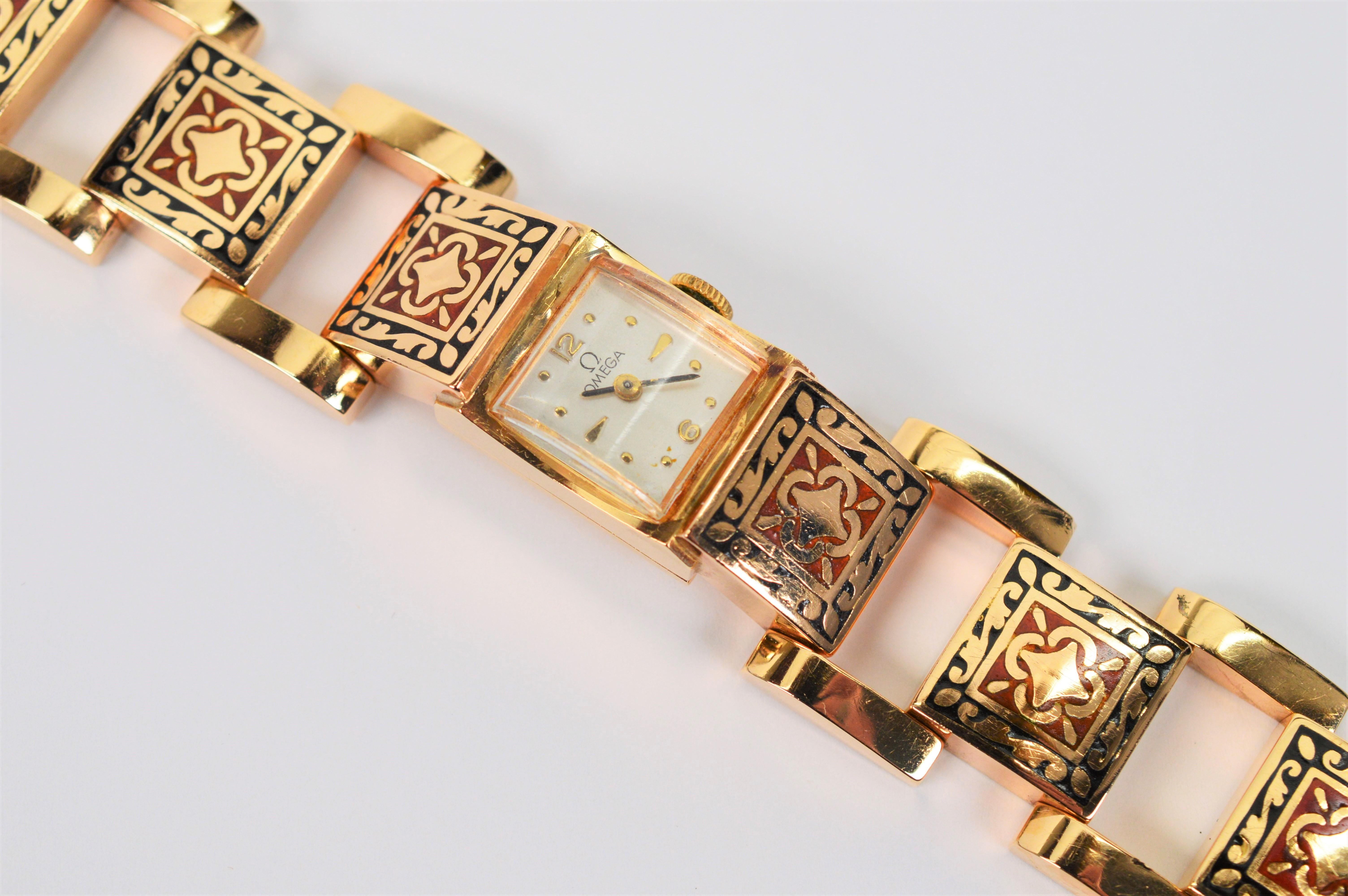 An artful renaissance inspired intricate pattern of red and black enamel inlay decorates each square link of fourteen karat 14K yellow gold along this fine Ladies Omega Bracelet Wrist Watch.
This uniquely attractive jewelry timepiece is a winder