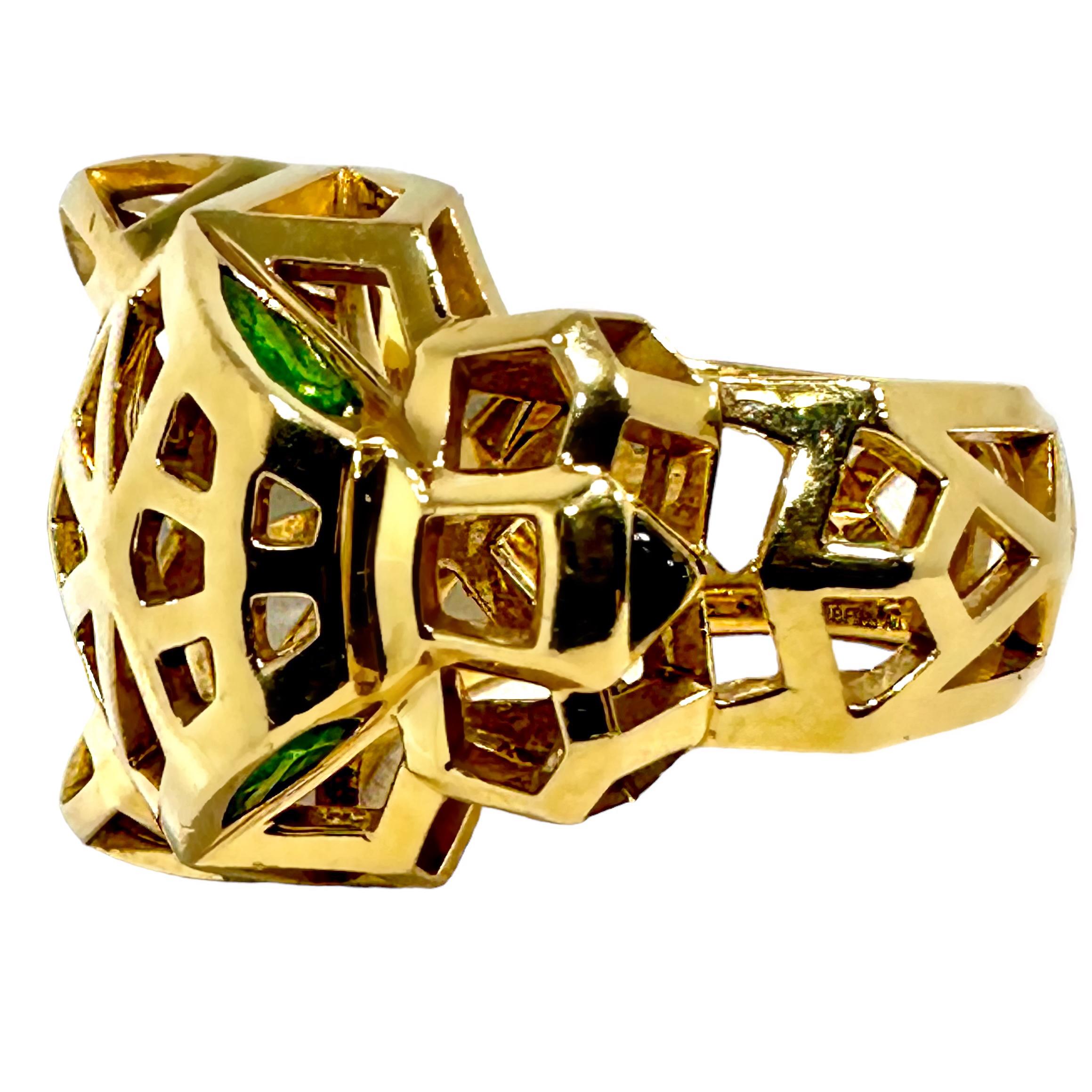 This ladies, French Cartier creation is astonishing and dramatic in both scale and design. The entire highly stylized and extremely dimensional panther head is pierced in geometric patterns over its entire surface. Large green tsavorite garnet eyes