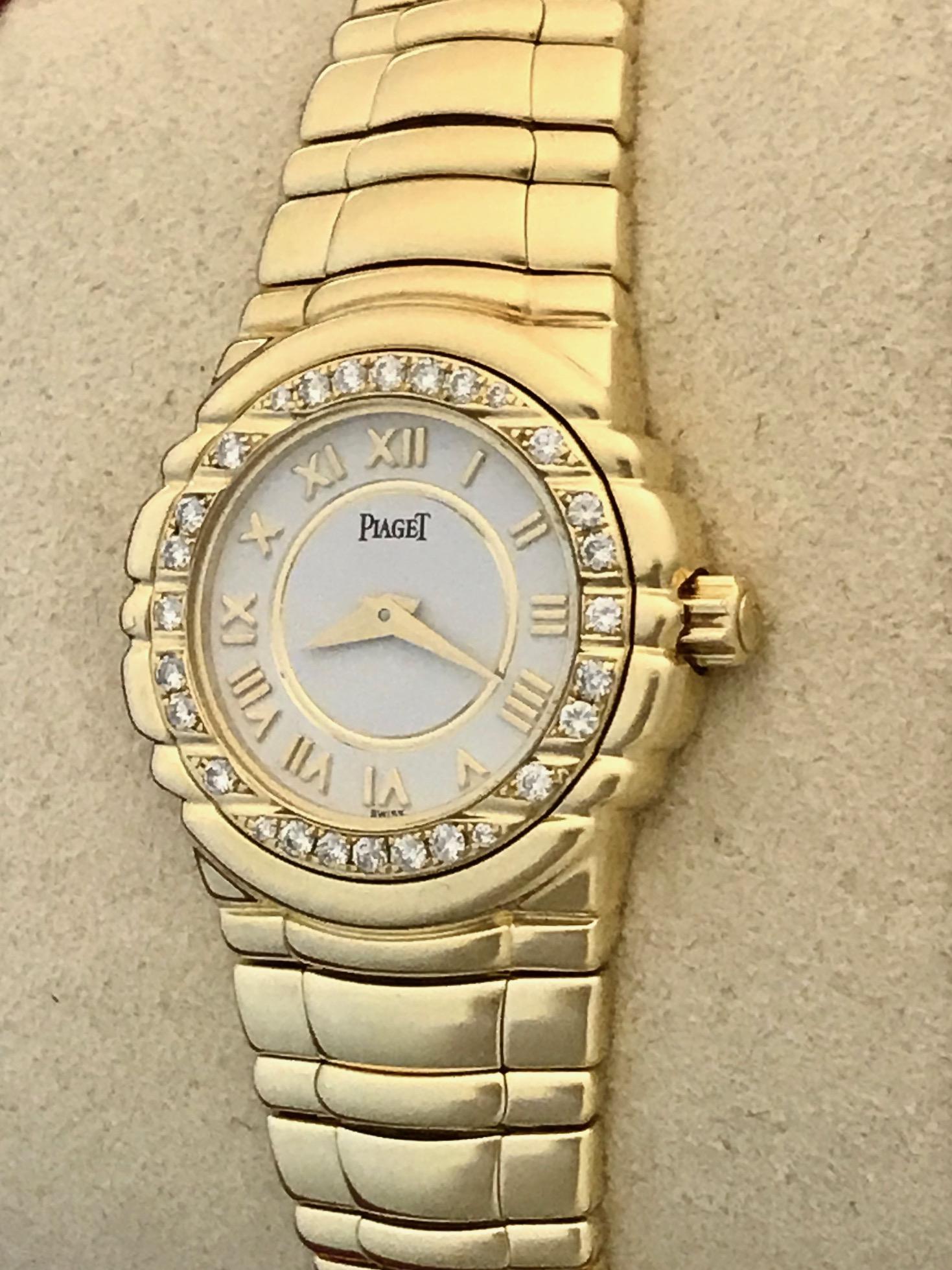 Stunning pre-owned ladies' Piaget Tanagra with factory Piaget diamond bezel and white dial with gold Roman numerals. White Dial with gold Roman numerals. 18k Yellow Gold integrated Piaget bracelet with deployant clasp. This watch is in beautiful