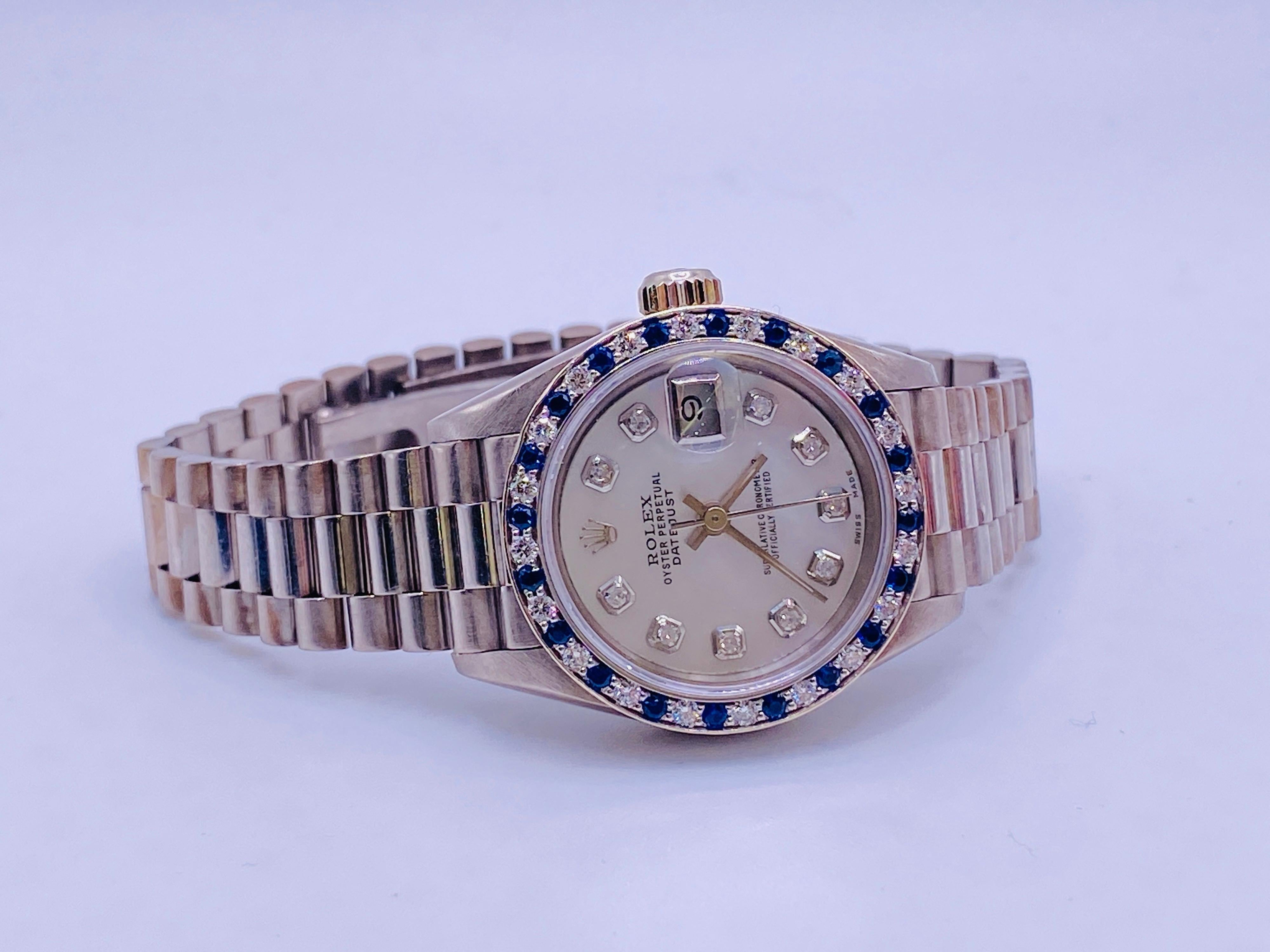 18k white gold ladies Datejust President Rolex with sapphire and diamond after market bezel. Includes box. Serial number E256631 Model 69179. Circa 1990. Personal inscription on case back added by original owner. Fully serviced. 26mm case.