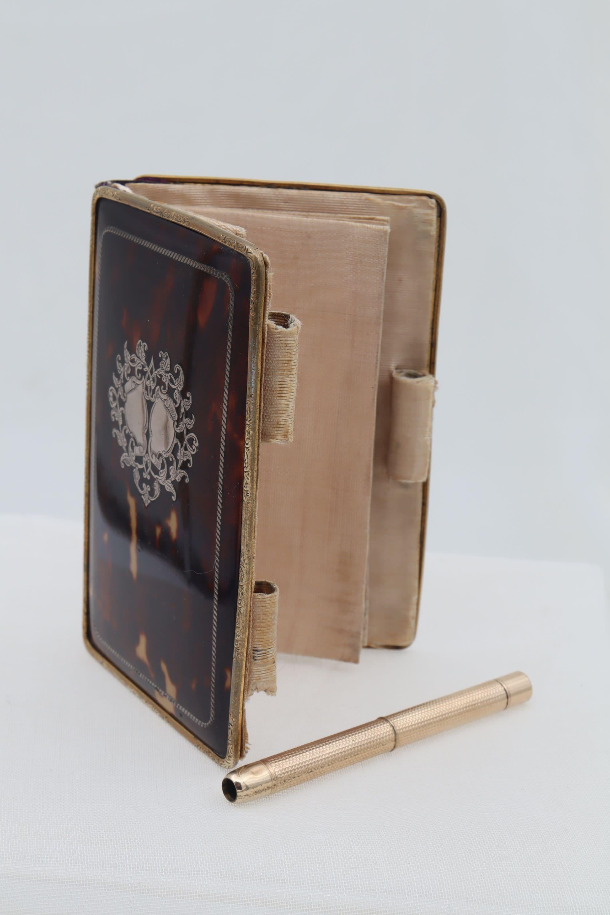 The front and rear tortoiseshell covers of this very good quality ladies aide memoire are held within an engraved gold frame. Inlaid to both covers is a rectangle of twisted silver wire giving a rope like frame and the front cover carries two silver
