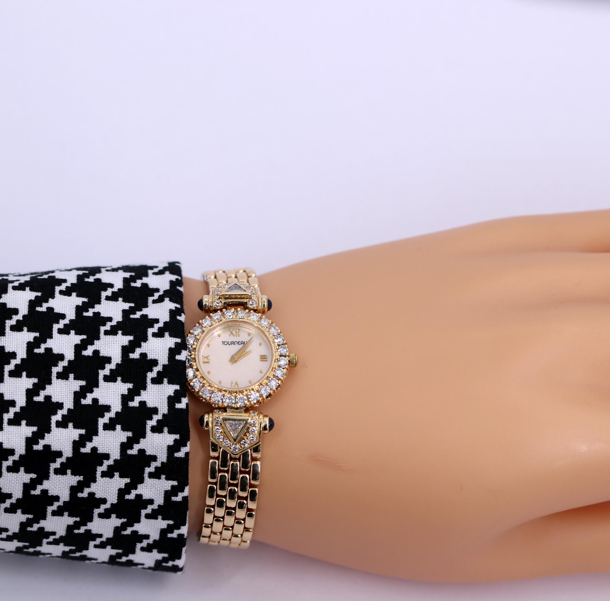 A women's 14K yellow gold Tourneau wristwatch, with a 24mm case, and a mother of pearl dial surrounded by a diamond bezel. Enhancing the appearance, are 4 cabochon cut sapphires at the beginning of the band. The bracelet begins with a trilliant cut