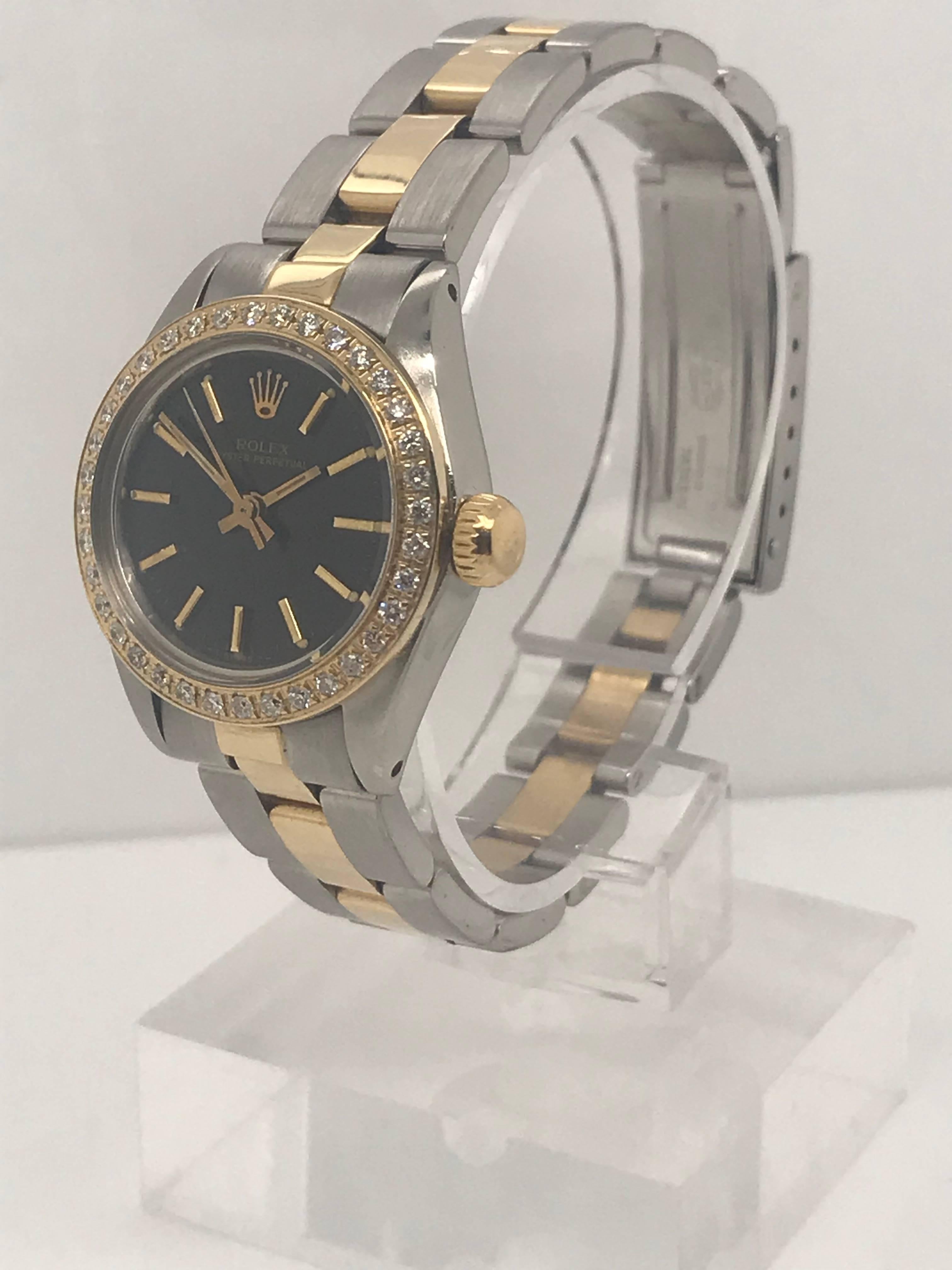 Two-tone, Ladies Oyster Perpetual Rolex made of 18 karat yellow gold and stainless steel with black dial and round diamond bezel. Circa 1980. 

This timepiece was recently serviced by a Rolex certified watchmaker. 
