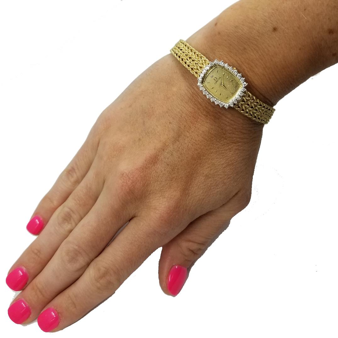14 Karat Yellow Gold Omega Ladies Quartz Watch on Woven Mesh Bracelet. 
The Bezel Contains 26 Round Diamonds Surrounding A Gold Tone Dial, Totaling 
Approximately 0.52 Carats. Total Length is 7 Inches With Adjustment For Slightly Tighter Fit.