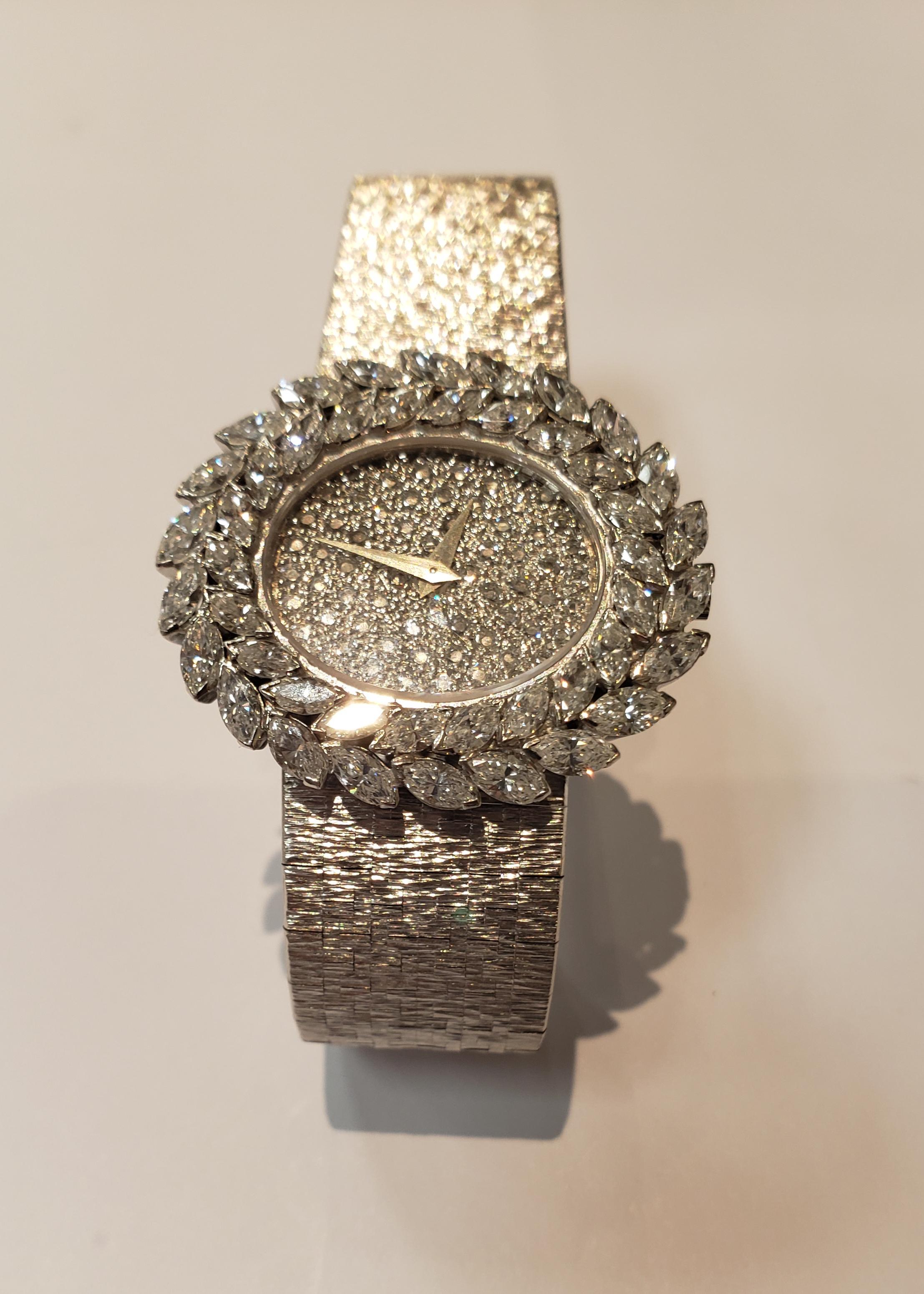 Circa 1980 ladies' 18 karat white gold Piaget watch with an east west oval pave diamond dial and a marquise diamond laurel leaf design bezel. Watch is on a textured integrated bracelet. Manual wind movement. Swiss made. Watch contains 4 carats total