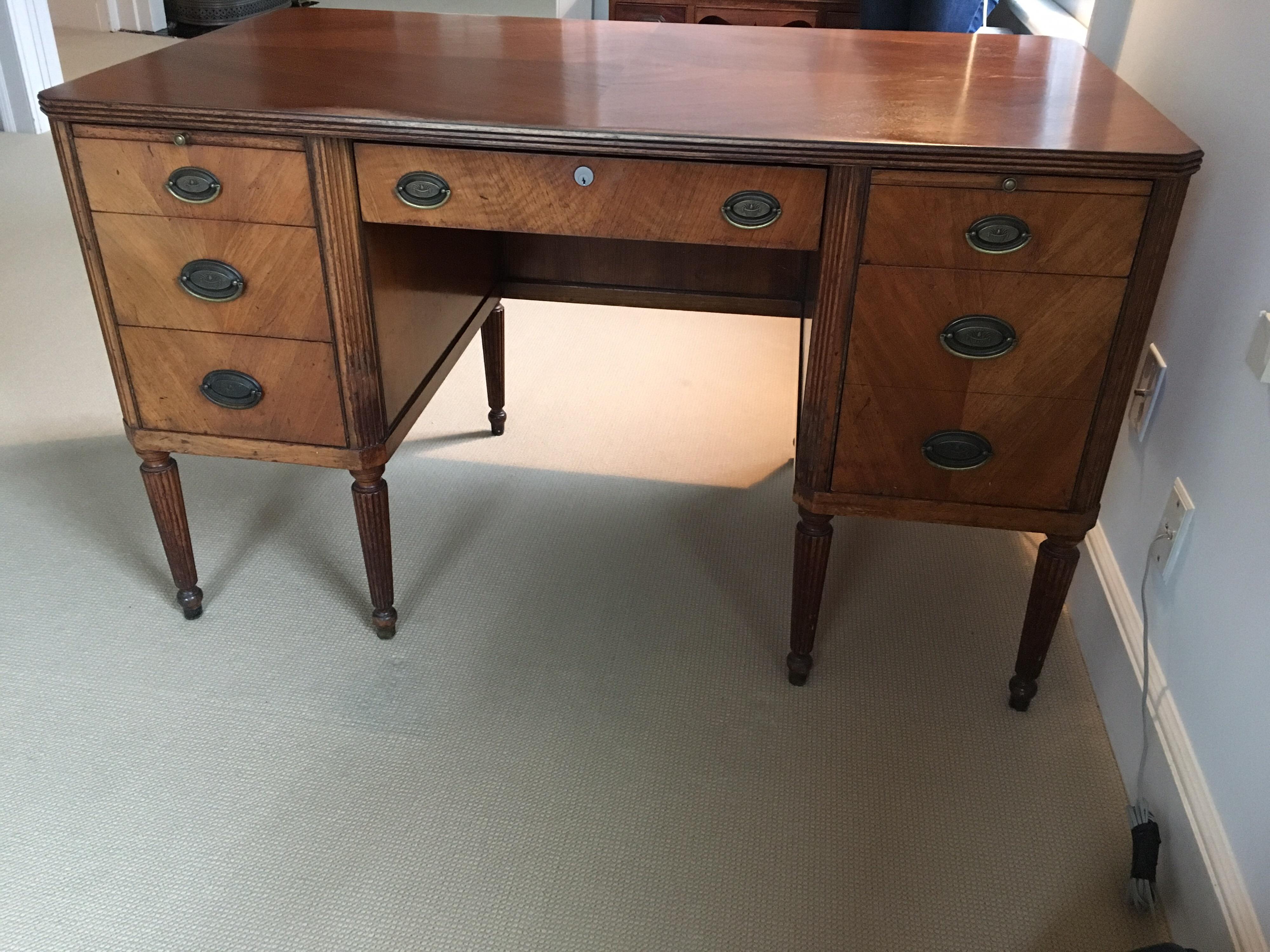 Ladies writing desk, circa 1920s
Three drawers on each side on a single drawer with lock. Two wood writing tops on either side of kneehole. Lovely wood matching on the top creating a diamond pattern. Book matching on the front and back panels. Wear