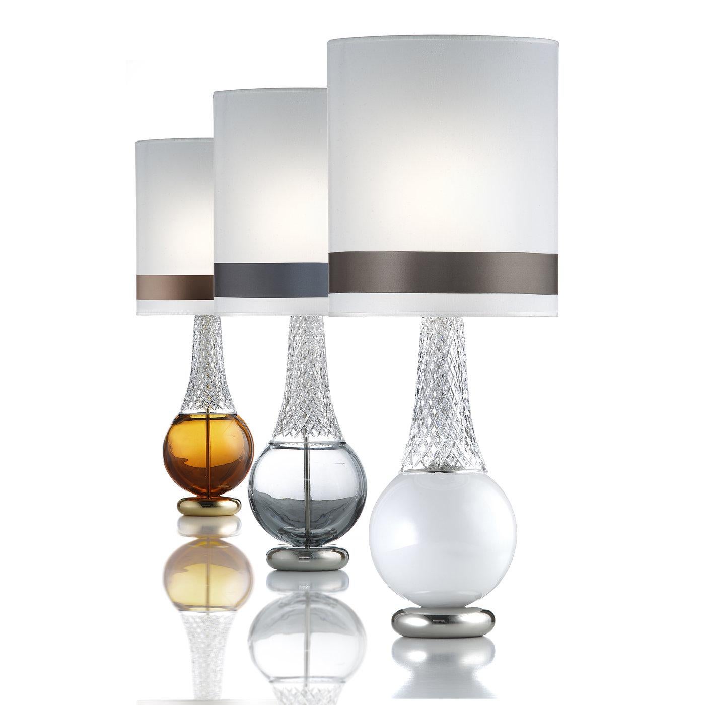 This superb table lamp is a striking example of exquisite craftsmanship and modern design. The structure in metal with a polished nickel finish rests on a round base on which the handcut 24 lead Italian crystal creates two entirely different