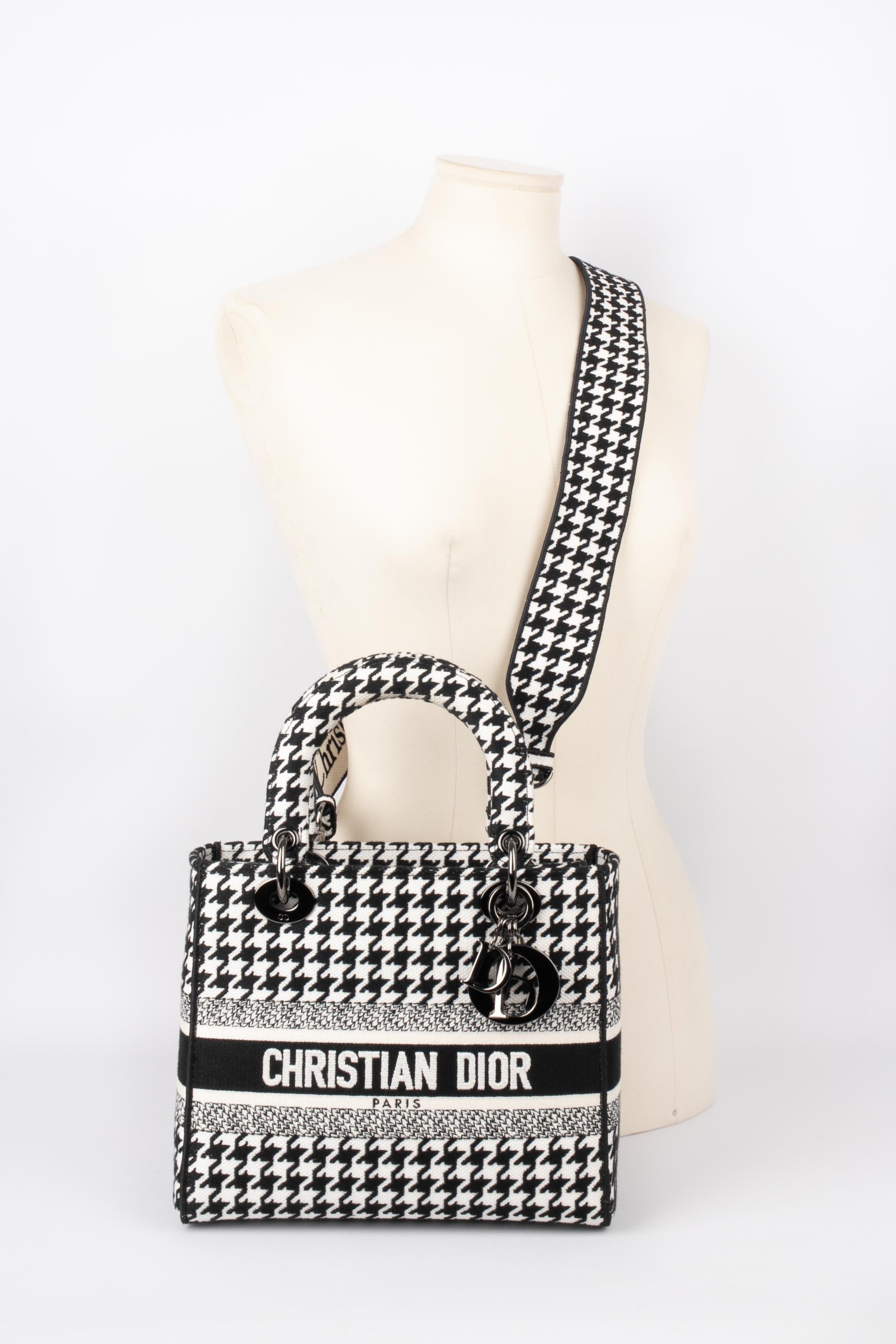 DIOR - Lady Dior bag in black and white houndstooth canvas, double handle, one of which holds charms bearing the name of the House, removable shoulder strap. Serial number present, collection 2022.

Condition:
Very good condition

Dimensions