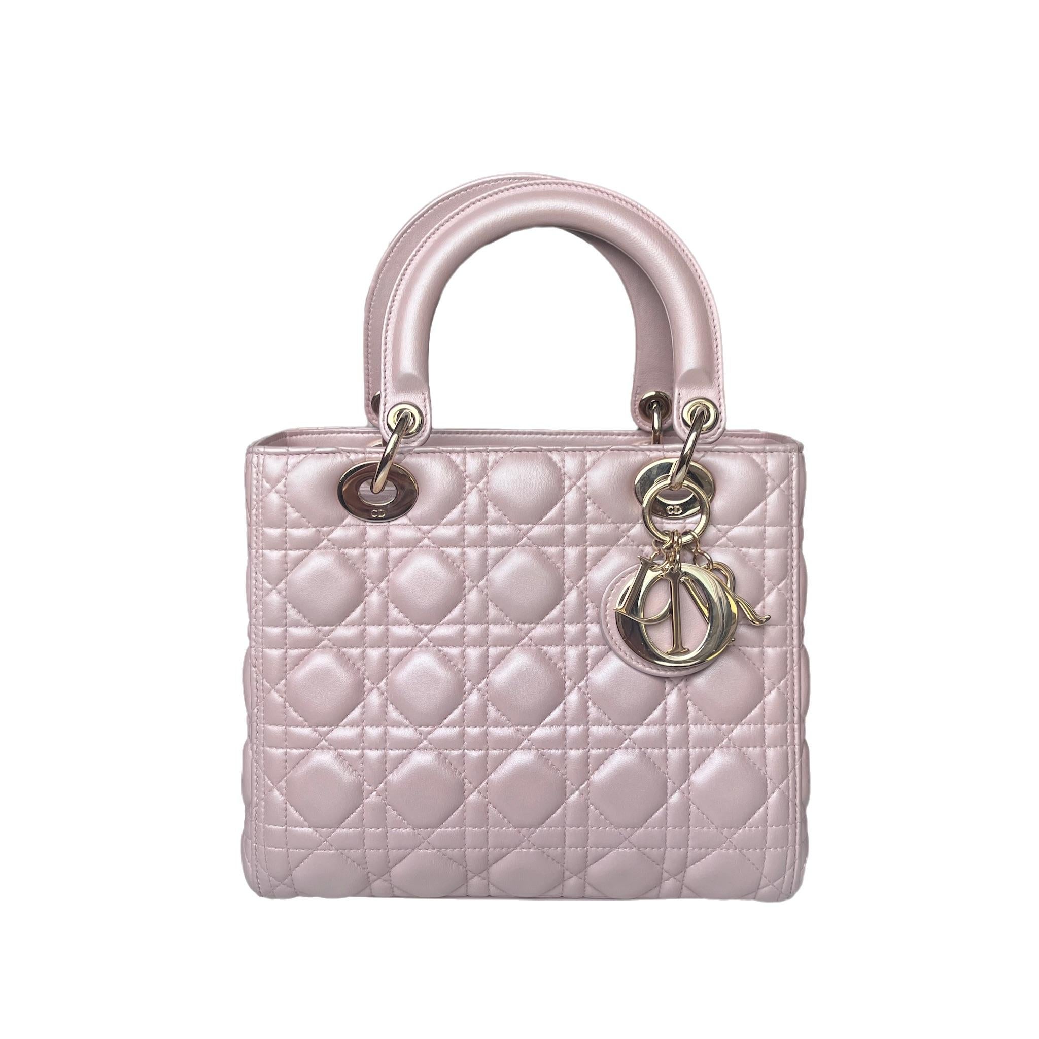 The Lady Dior bag is an epitome of elegance and beauty. Accentuate your look with the timeless style of Medium Lady Dior, crafted in Pearlescent Pink Lambskin Leather. This classic bag features a cannage stitch, creating a beautiful silhouette and