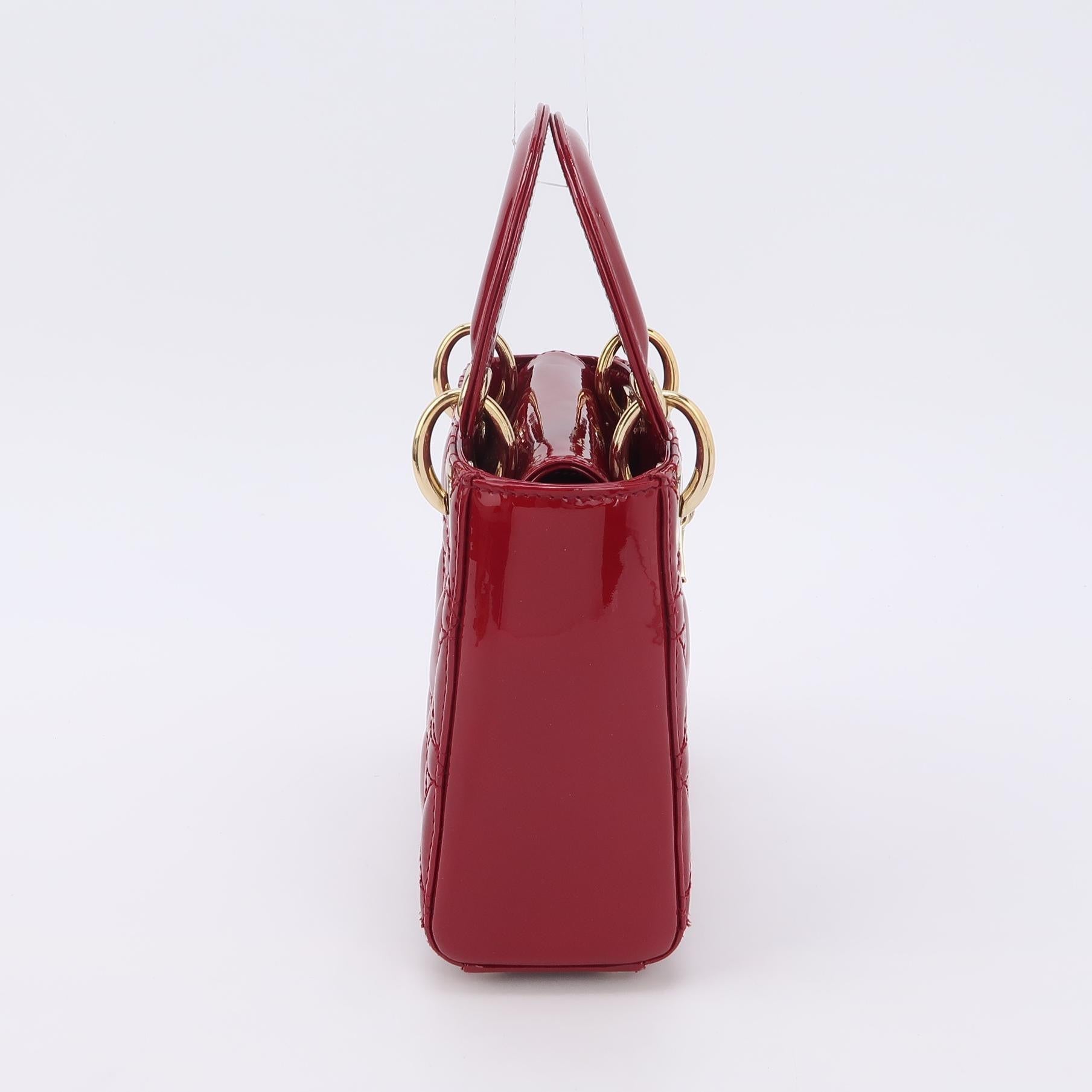 Lady Dior Mini Handbag Burgundy Red Patent Leather Gold-tone Chain Strap
These are professional photos of the actual bag.
This Lady Dior Mini handbag features a stunning red color in patent leather decorated with gold hardware, gold embellished