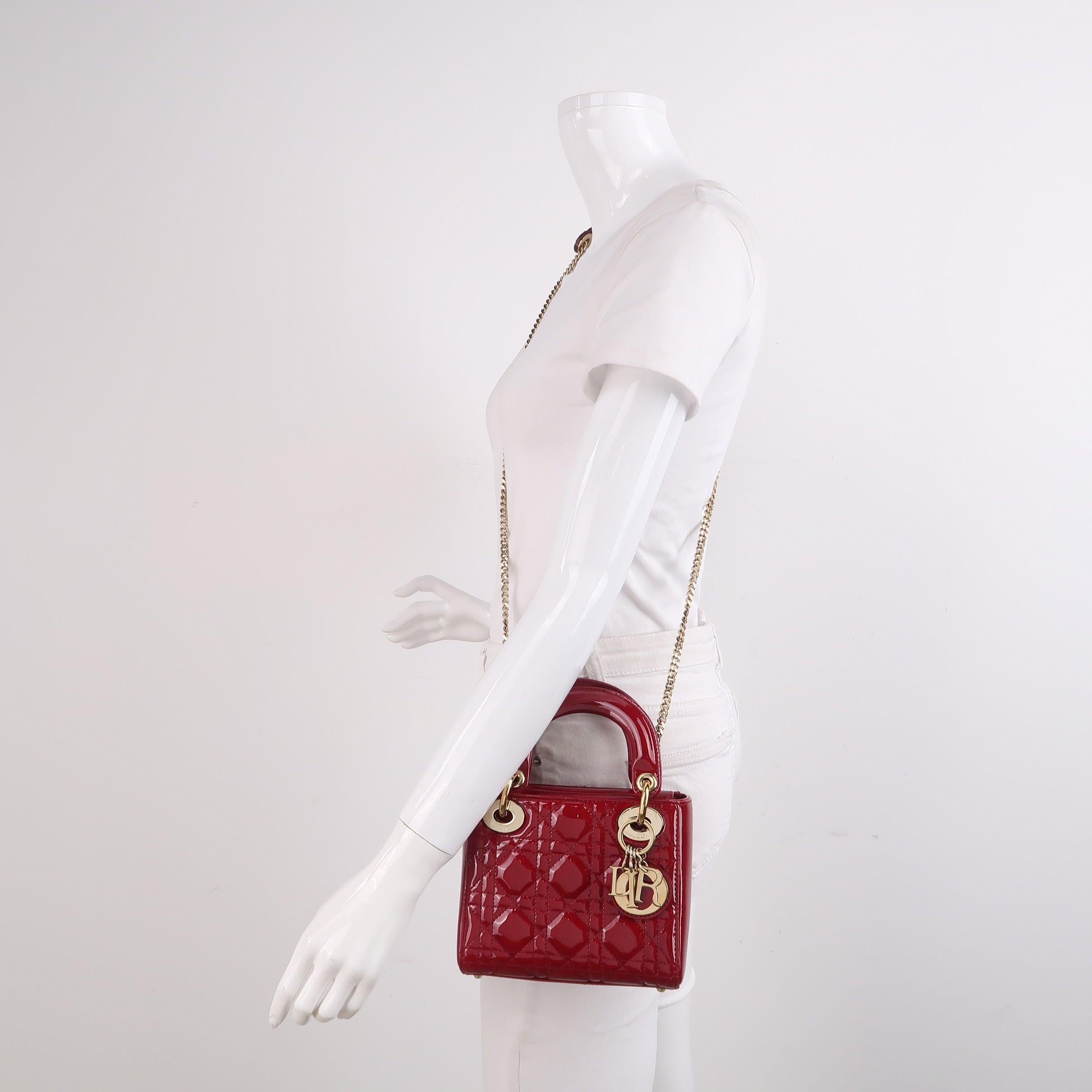 This Lady Dior Mini handbag features a stunning red color in patent leather decorated with gold hardware, gold embellished chain strap, making it an ideal accessory for any stylish woman who dares to make a bold statement with their accessory. The