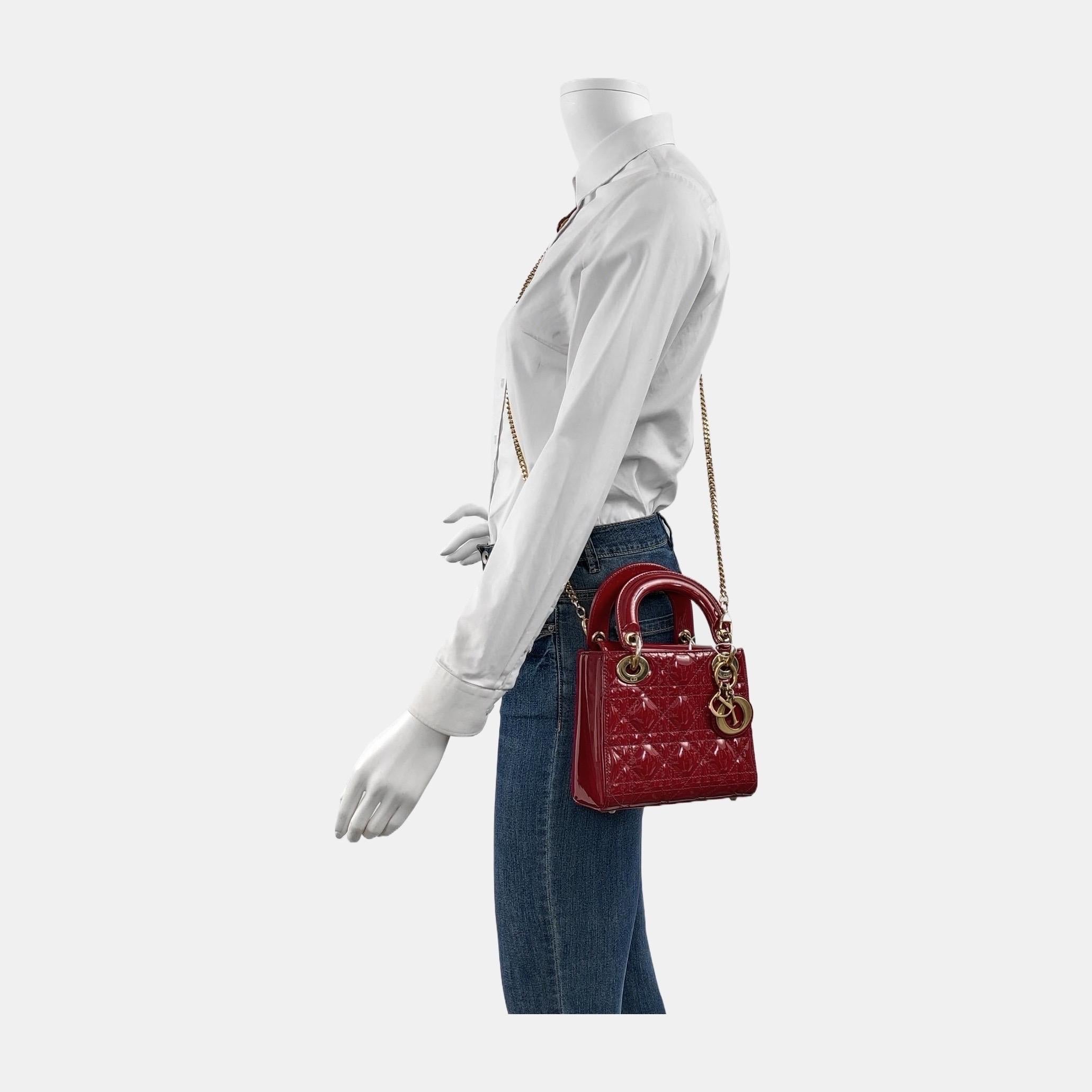 This Lady Dior Mini handbag features a stunning red color in patent leather decorated with gold hardware, gold embellished chain strap, making it an ideal accessory for any stylish woman who dares to make a bold statement with their accessory. The