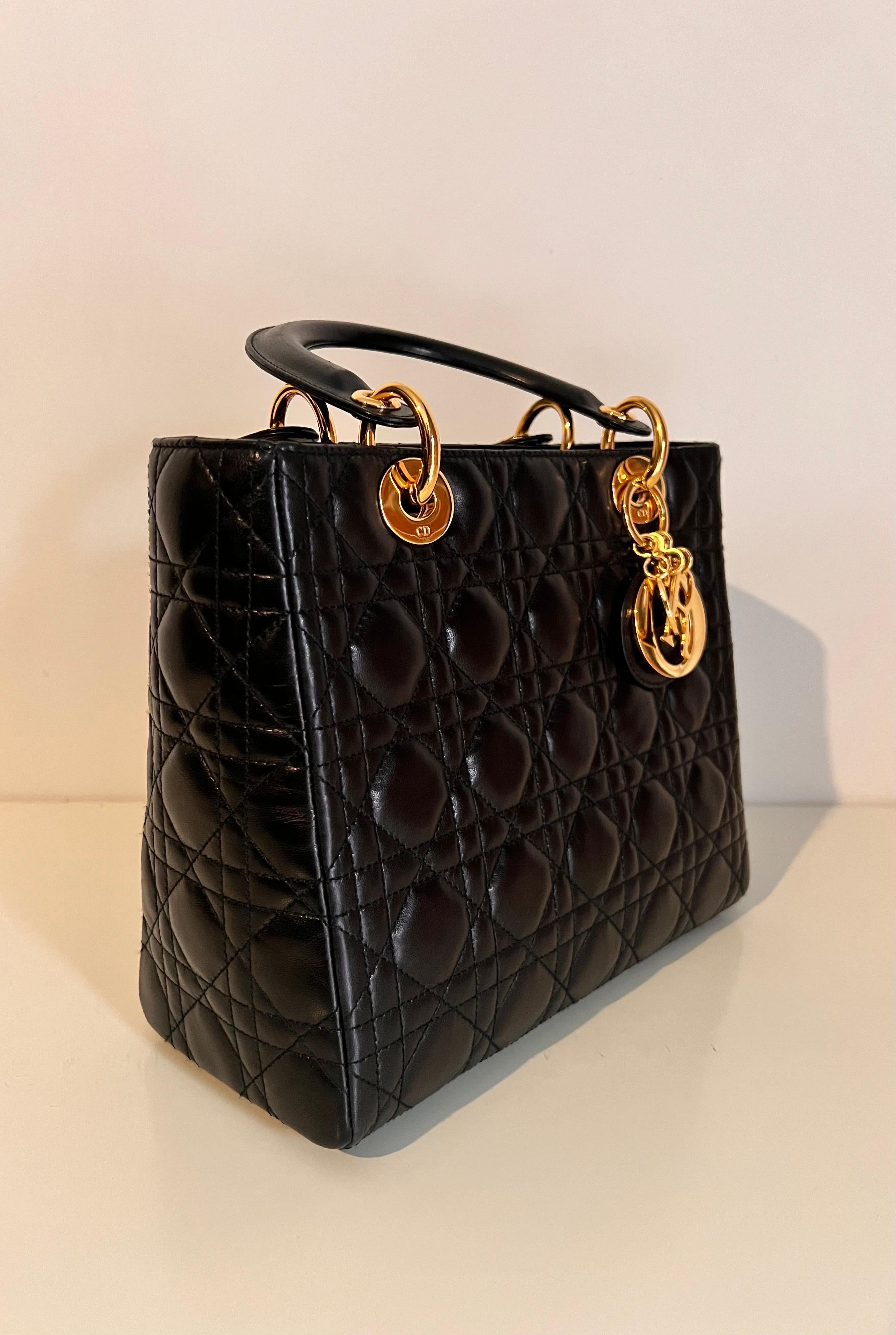 Lady DIOR quilted handbag in black with gold Dior hardware, famously worn by Princess Diana.  The Lady Dior bag epitomizes the House's vision of elegance and beauty. Sleek and refined, the timeless creation is crafted in black lambskin with Cannage
