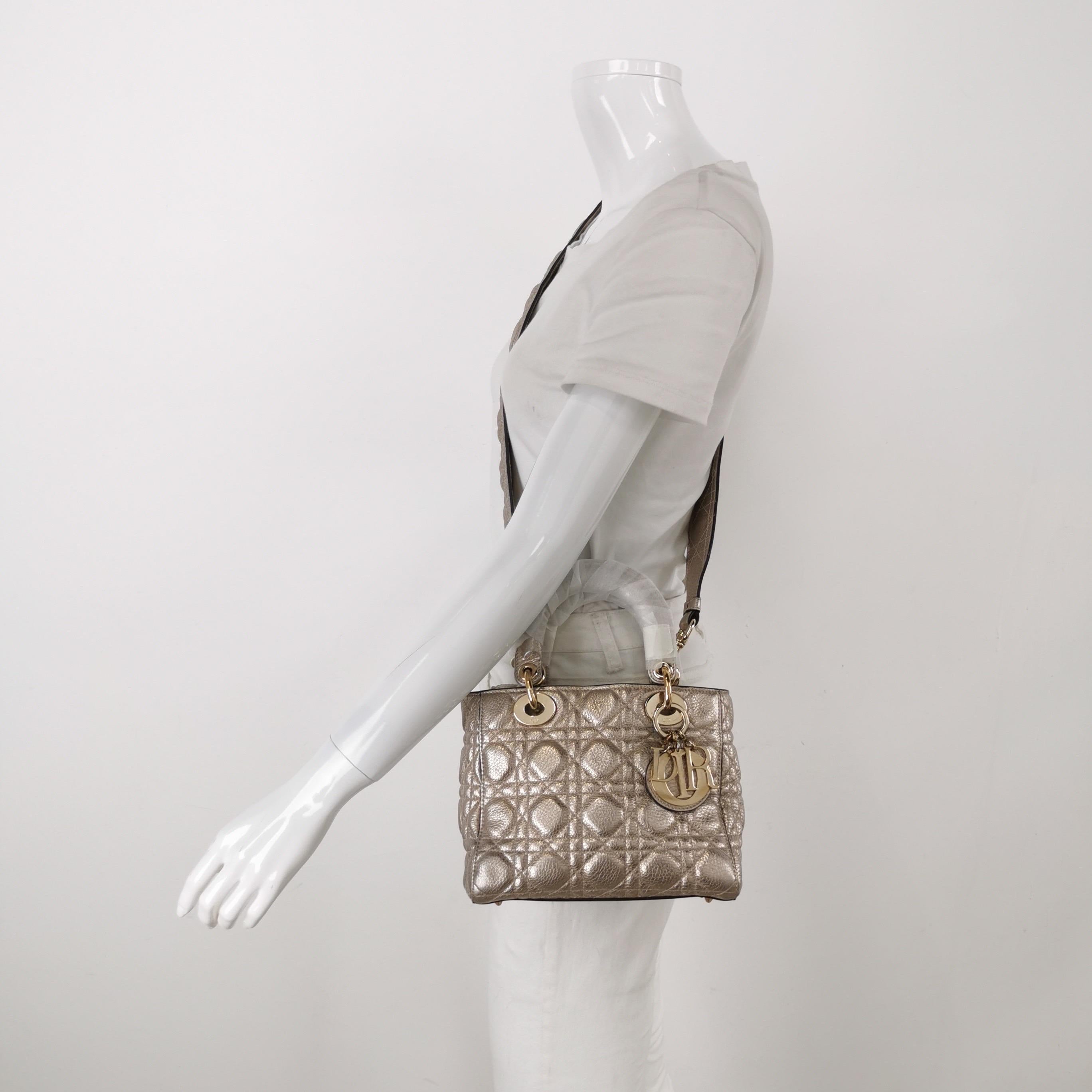 This Lady Dior Small Supple Calfskin Leather Gold Cannage Handbag with Strap is crafted from supple calfskin leather and features a unique cannage stitch. Unlike the iconic Lady Dior, this version has a more casual look due to its intentionally
